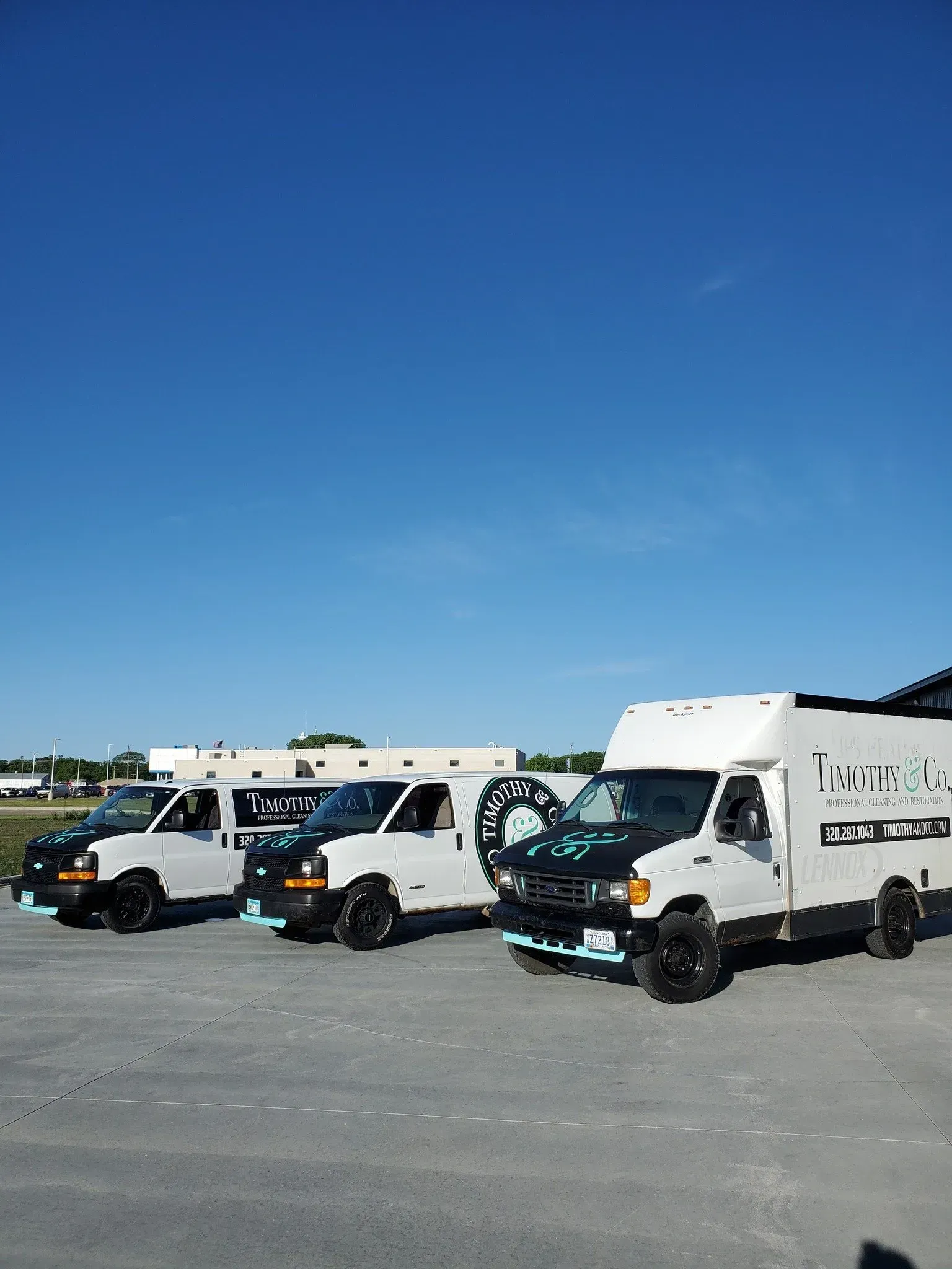 A row of vans are parked in a parking lot