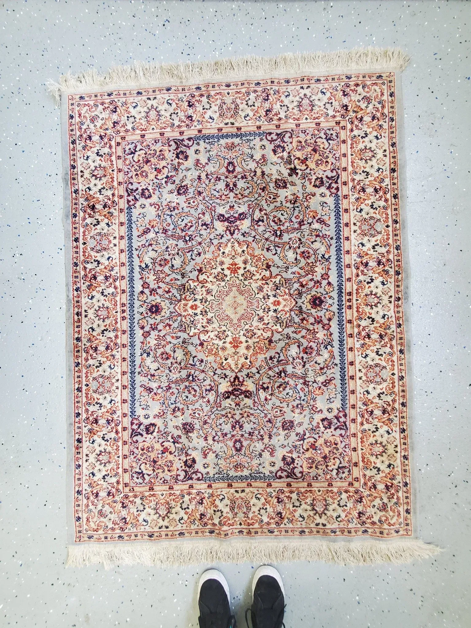 A person is standing next to a rug on the floor