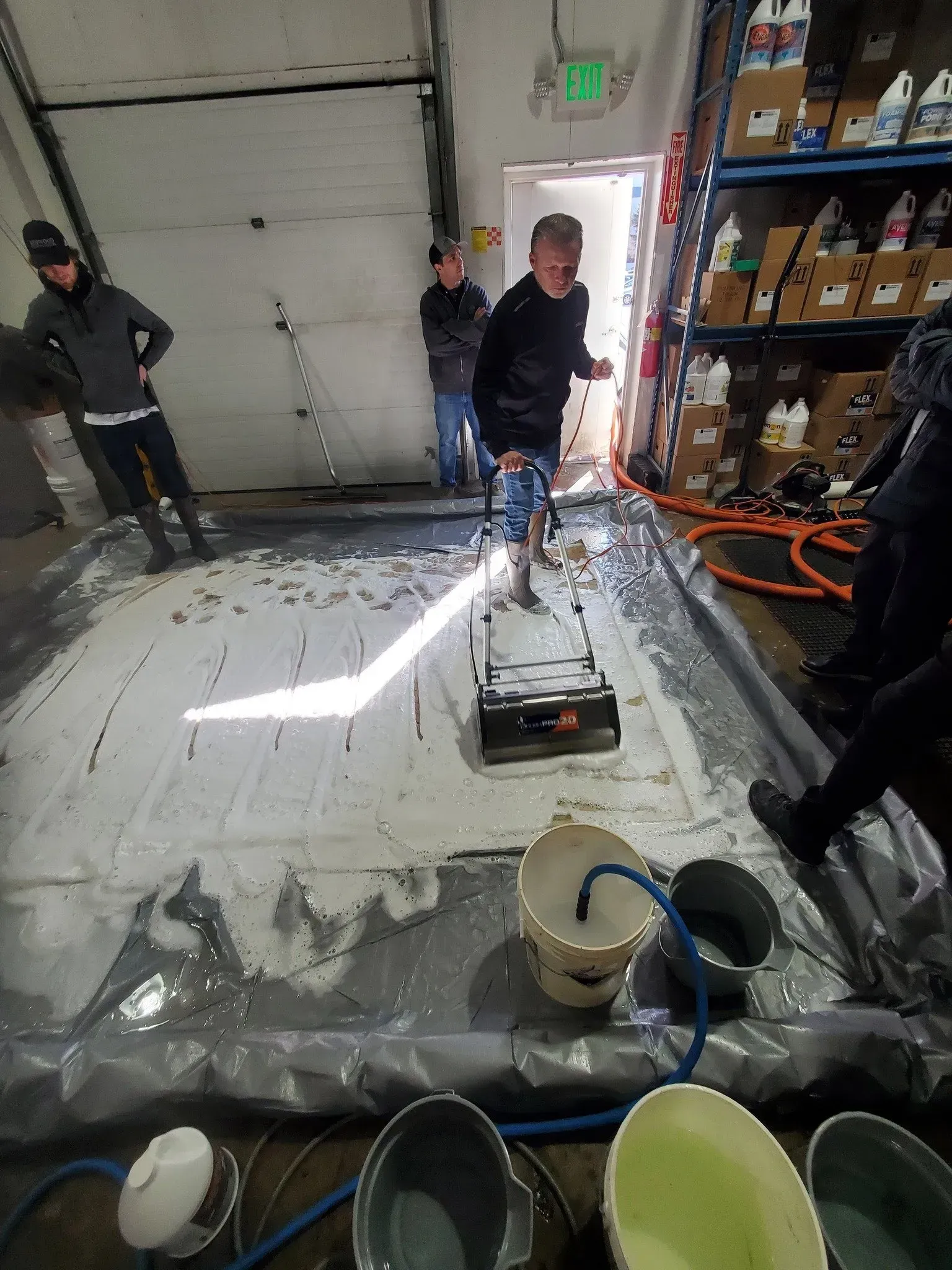 A group of men are standing around a table with buckets of paint.