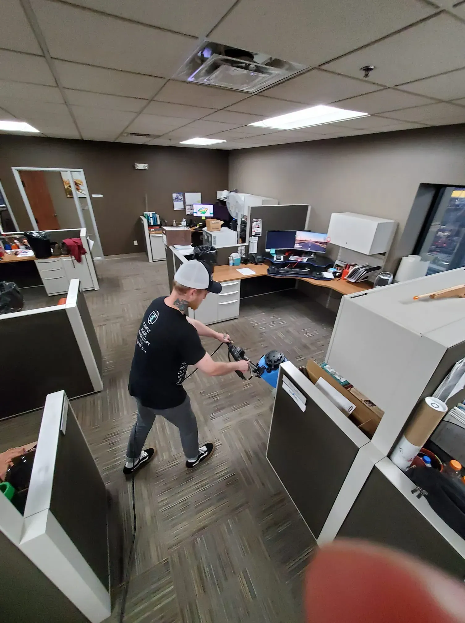 A man is spraying disinfectant on the floor of an office.
