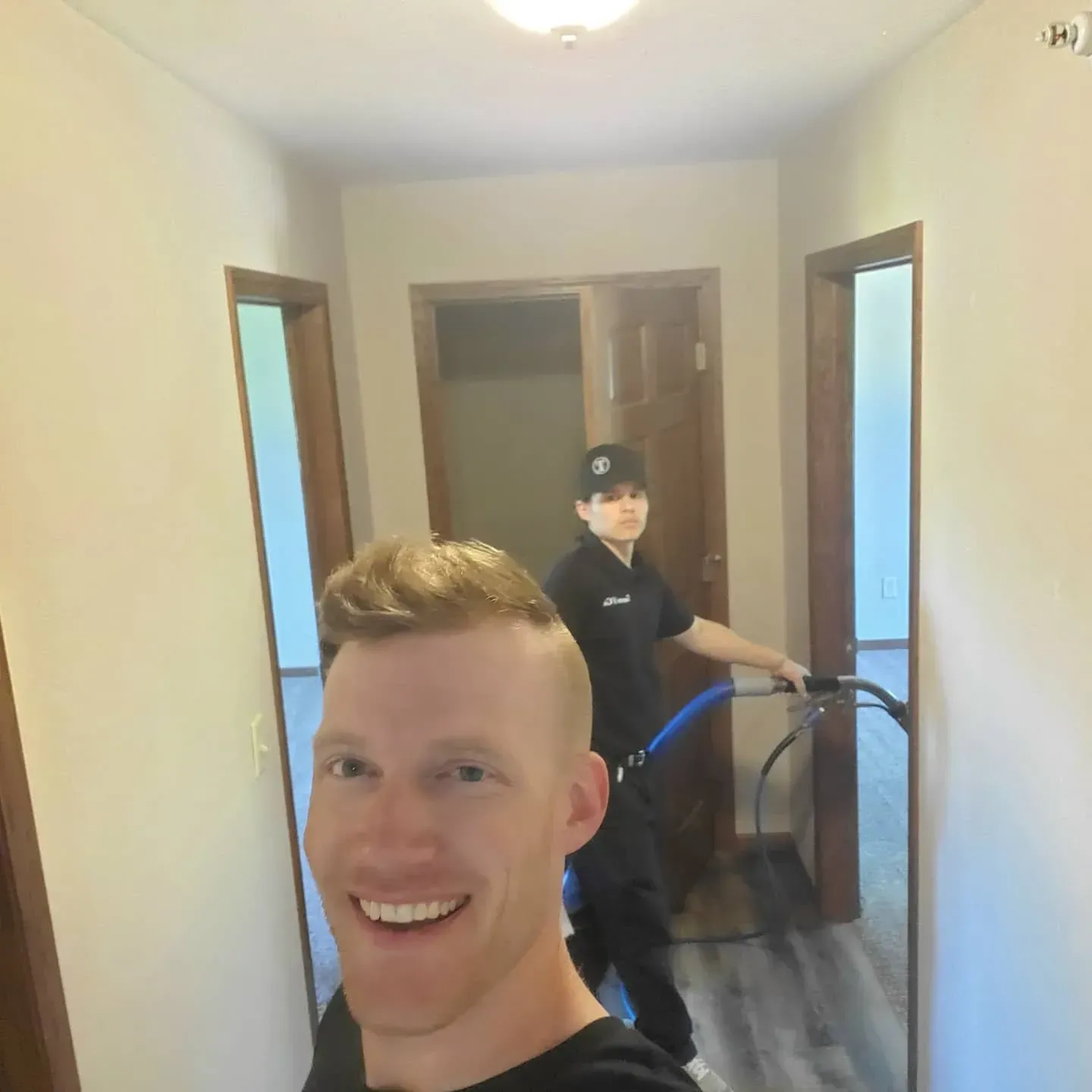 A man in a black shirt is smiling in a hallway