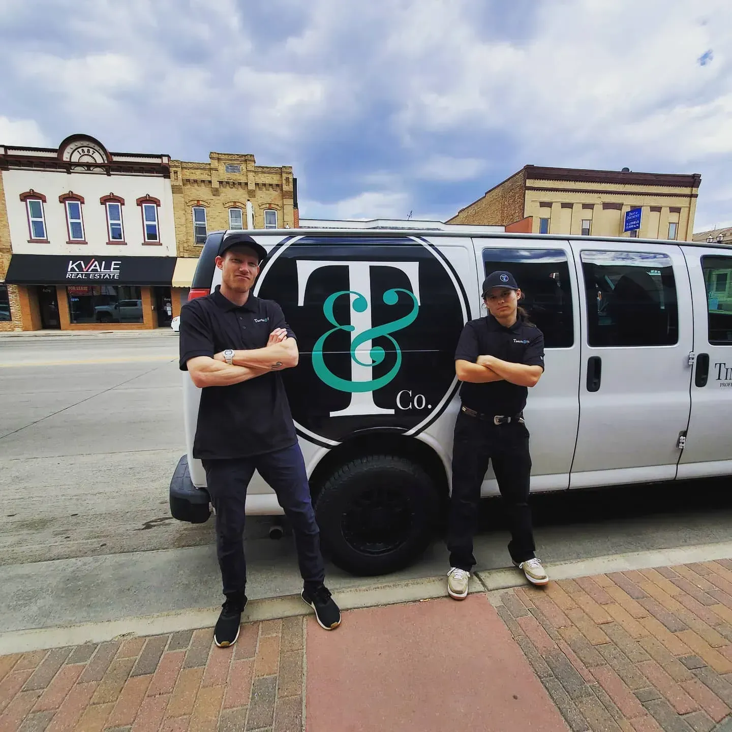 Two men standing in front of a van that says t & co.