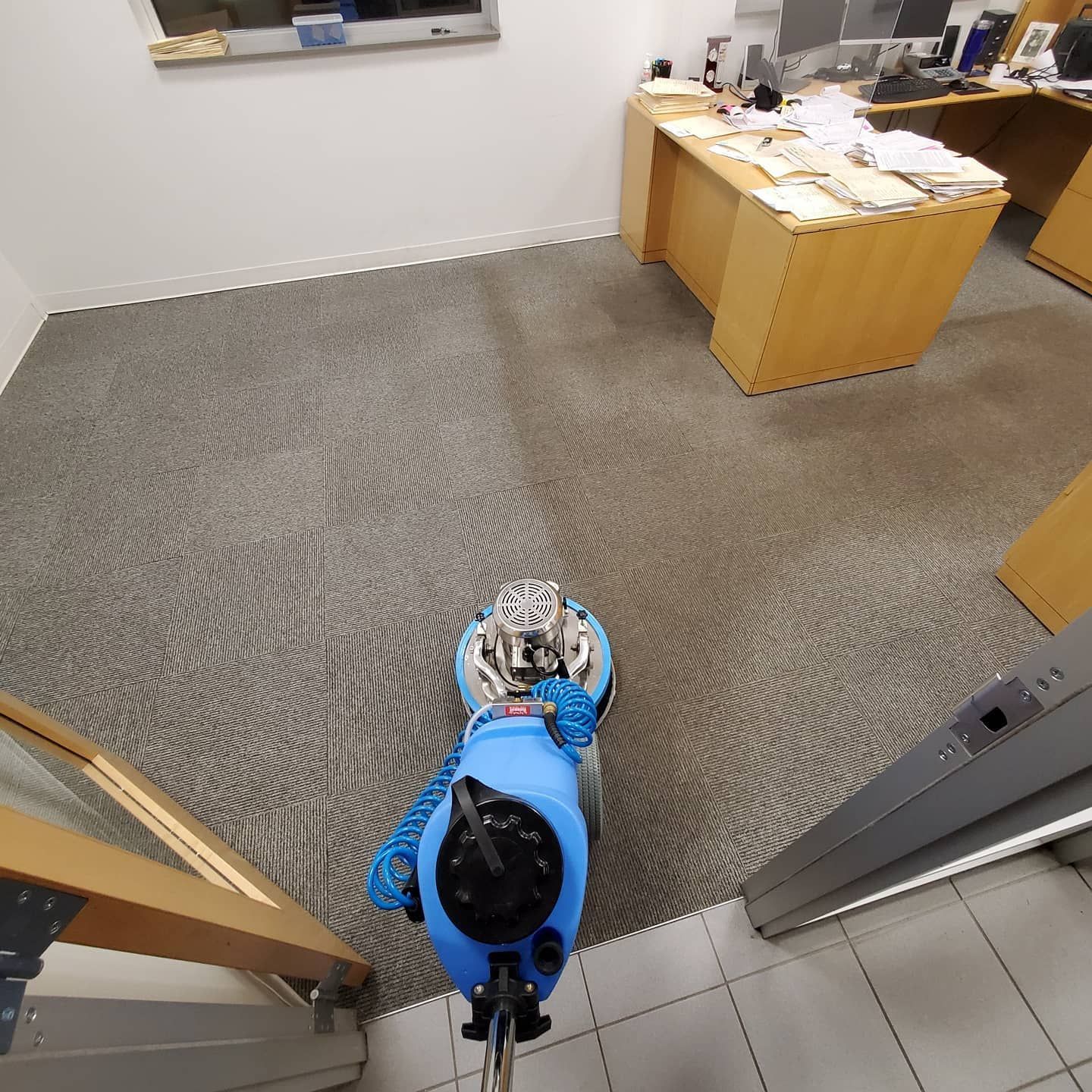 A person is using a machine to clean a carpet in an office