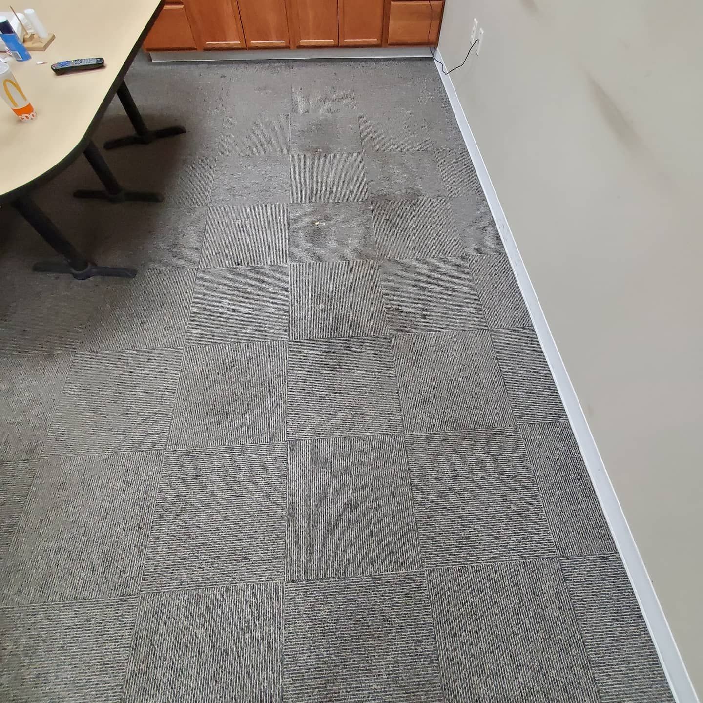 A dirty carpet in a room with a desk and cabinets.