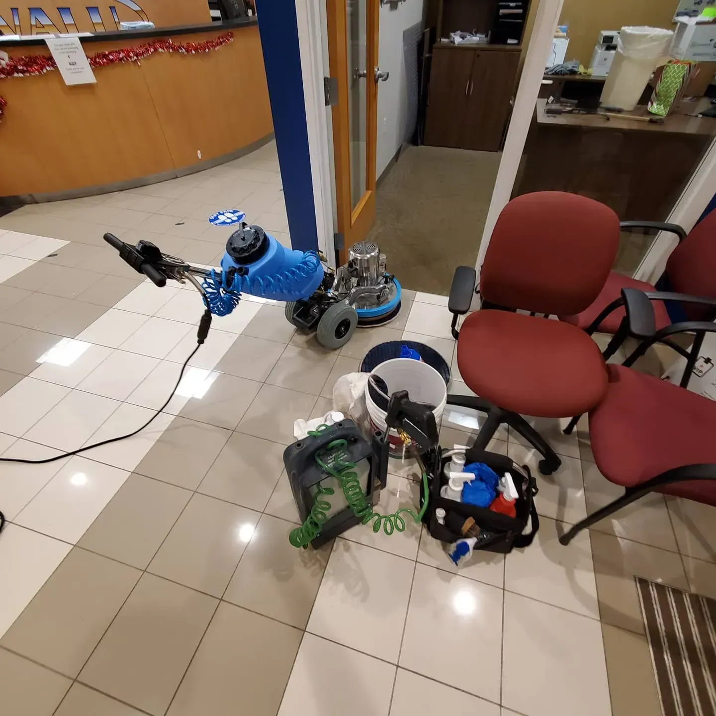 A vacuum cleaner is sitting on a tiled floor next to chairs
