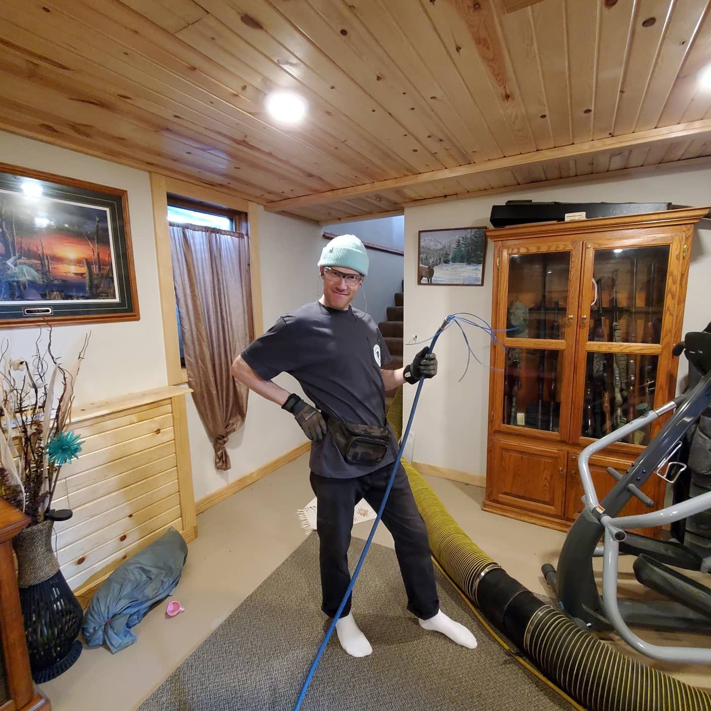 A man is standing in a room holding a hose