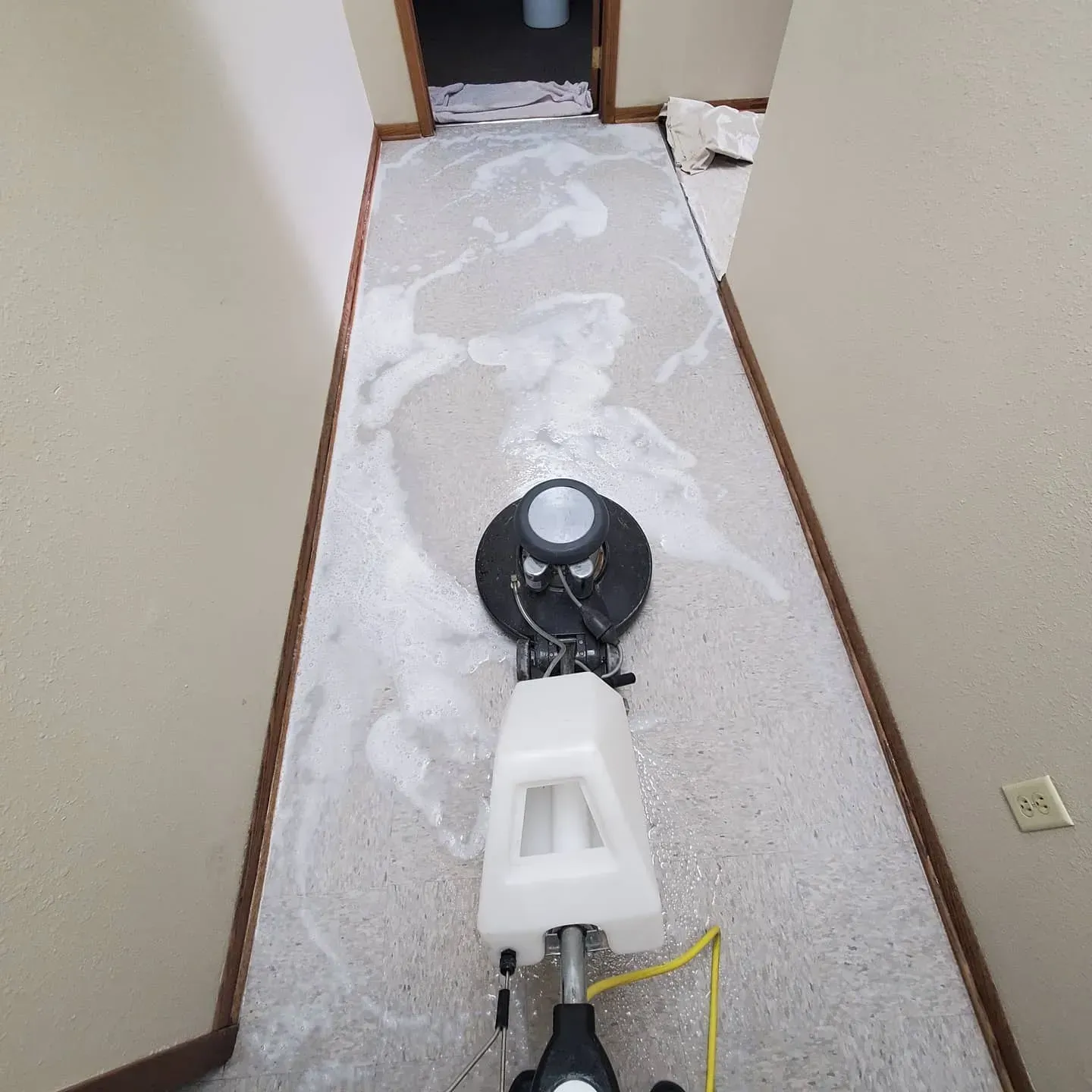 A machine is cleaning a carpet in a hallway.
