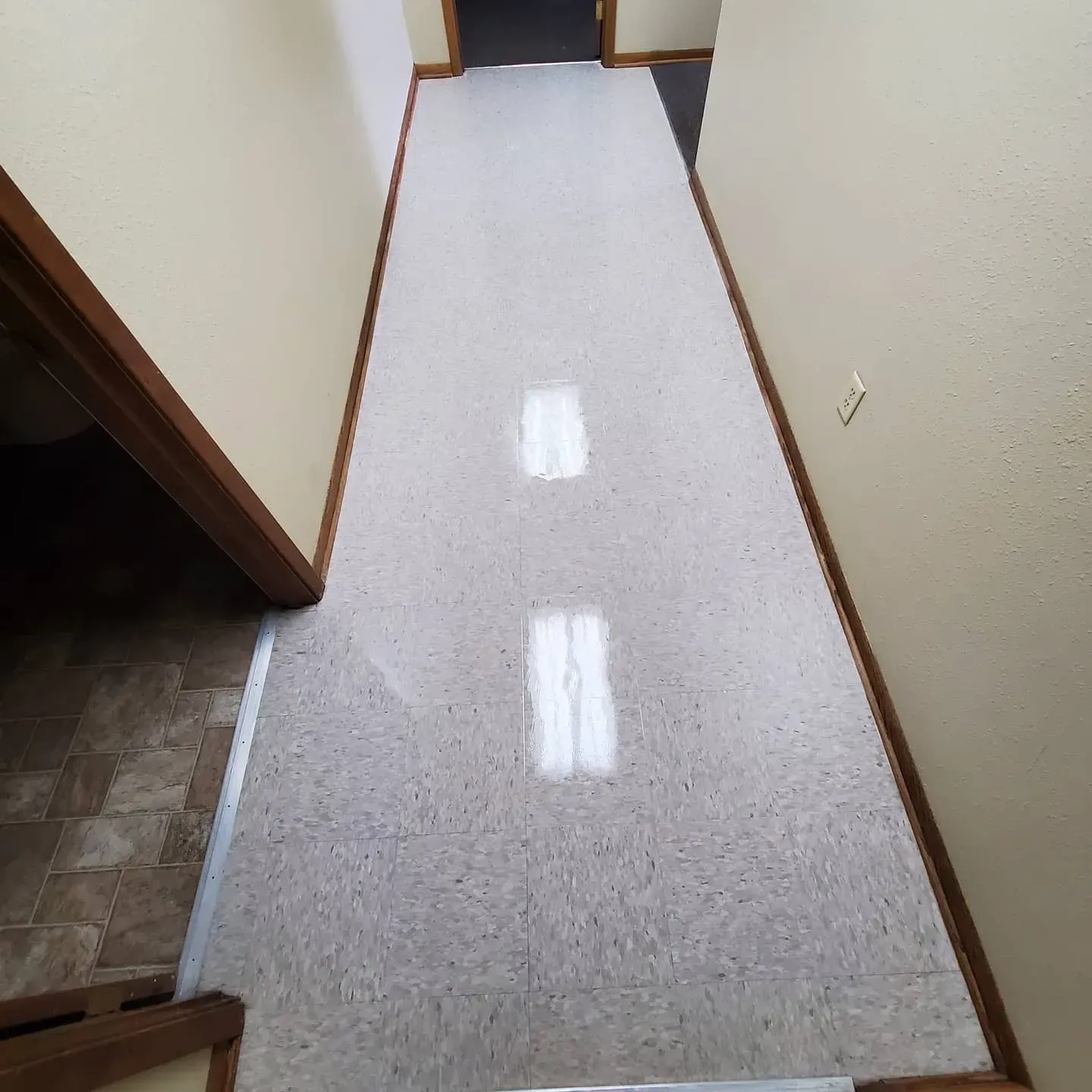 A long hallway with a white carpet and two lights on the floor.