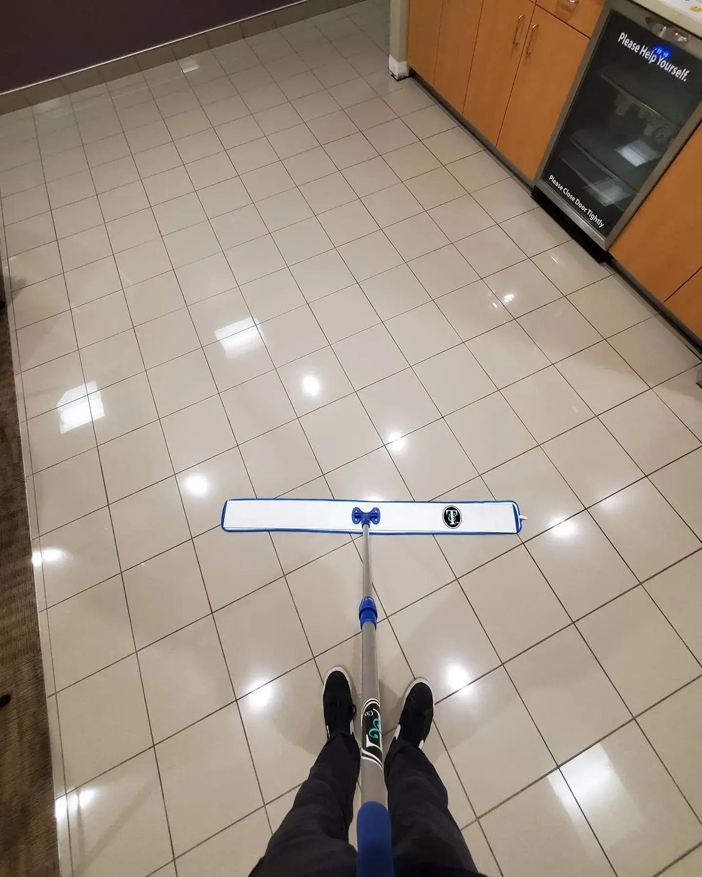 A person is standing on a tiled floor with a mop.