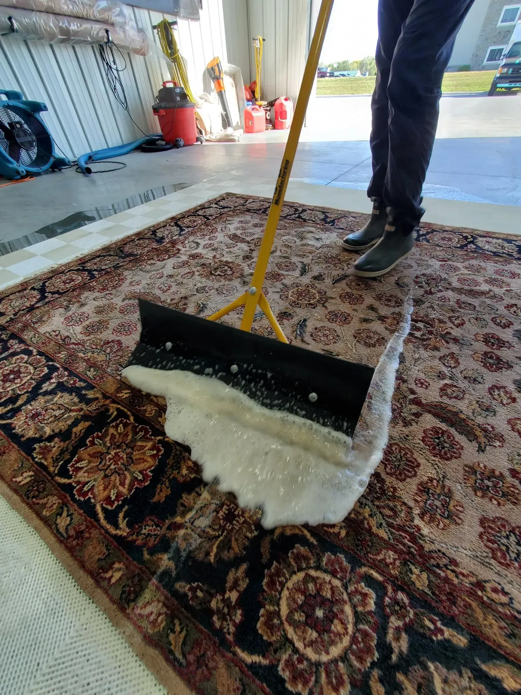 A person is cleaning a rug with a broom.