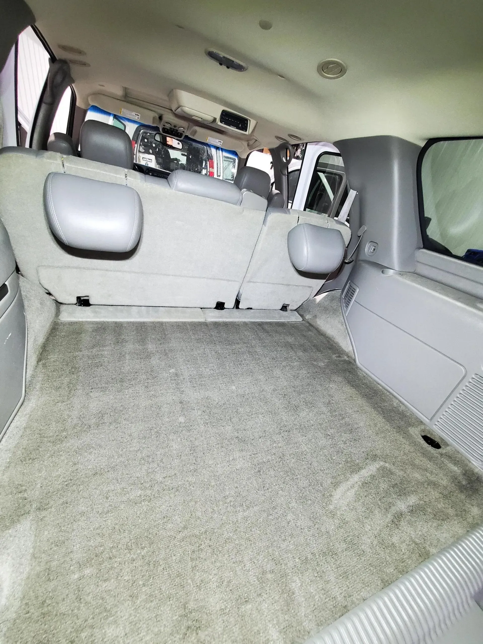 The back seat of a car with a carpeted floor.