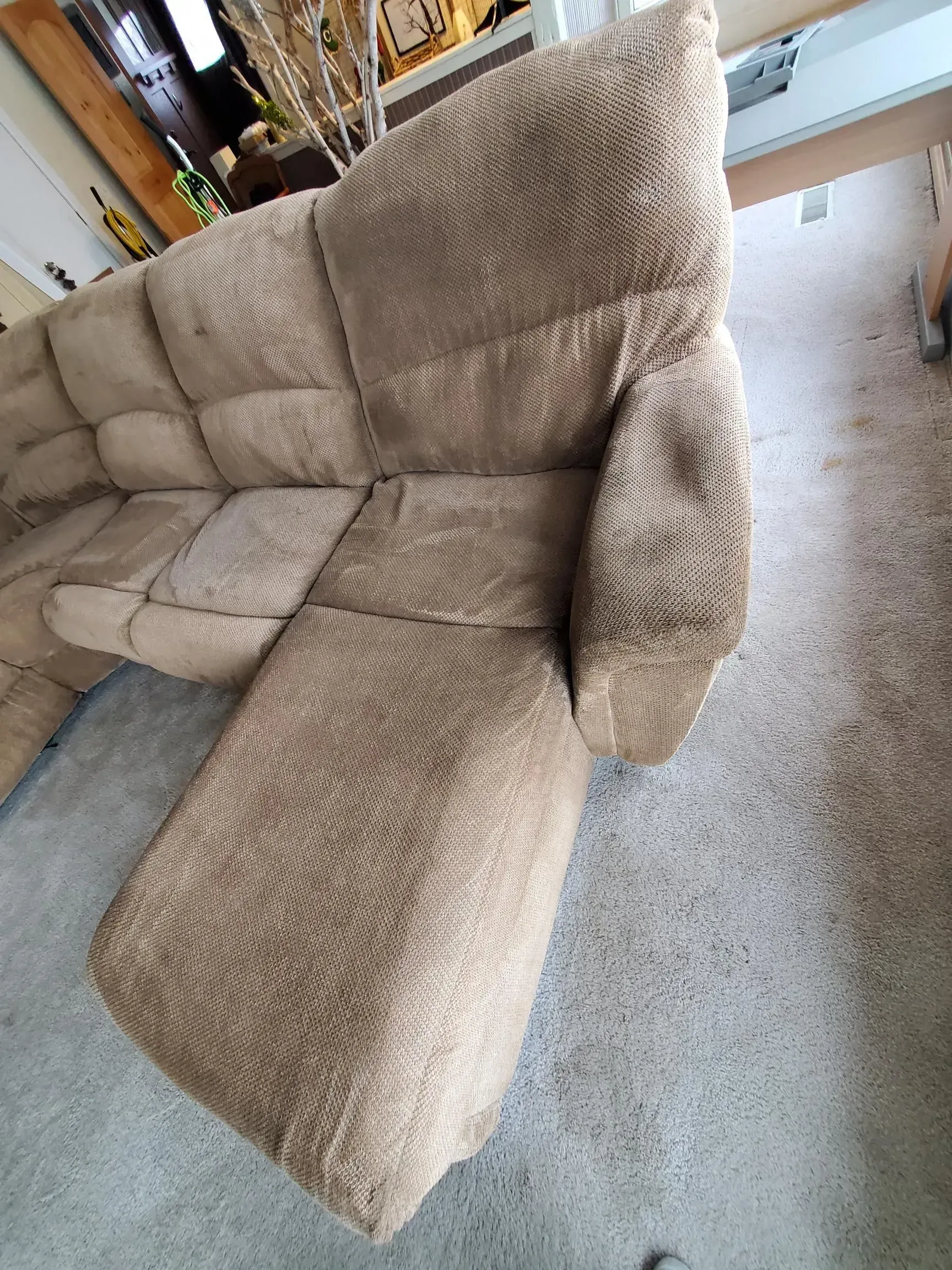 A brown sectional couch is sitting on a carpeted floor in a living room.