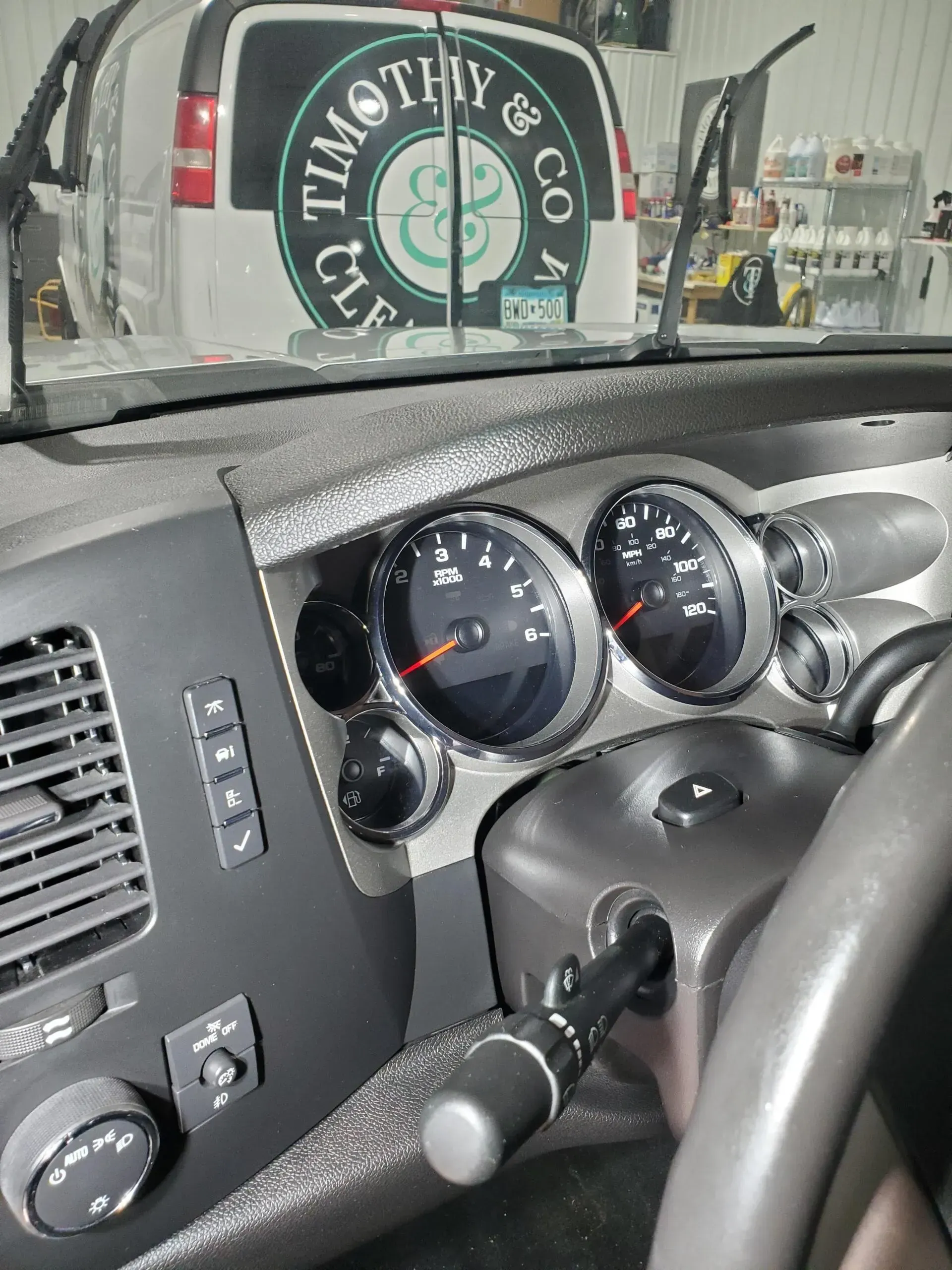 A dashboard of a car with a van in the background that says timothy & co.