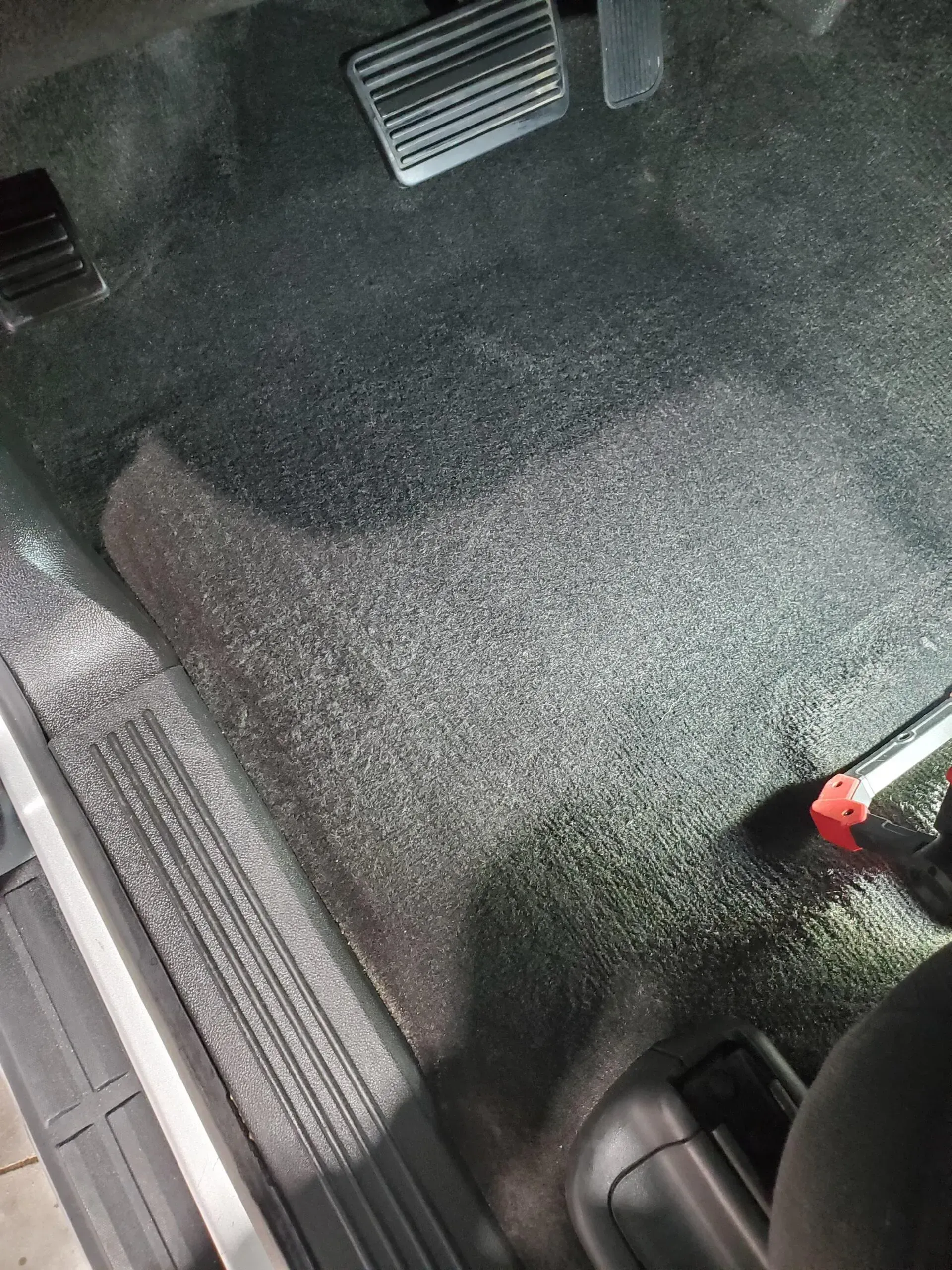 A person is cleaning the floor of a car with a vacuum cleaner.