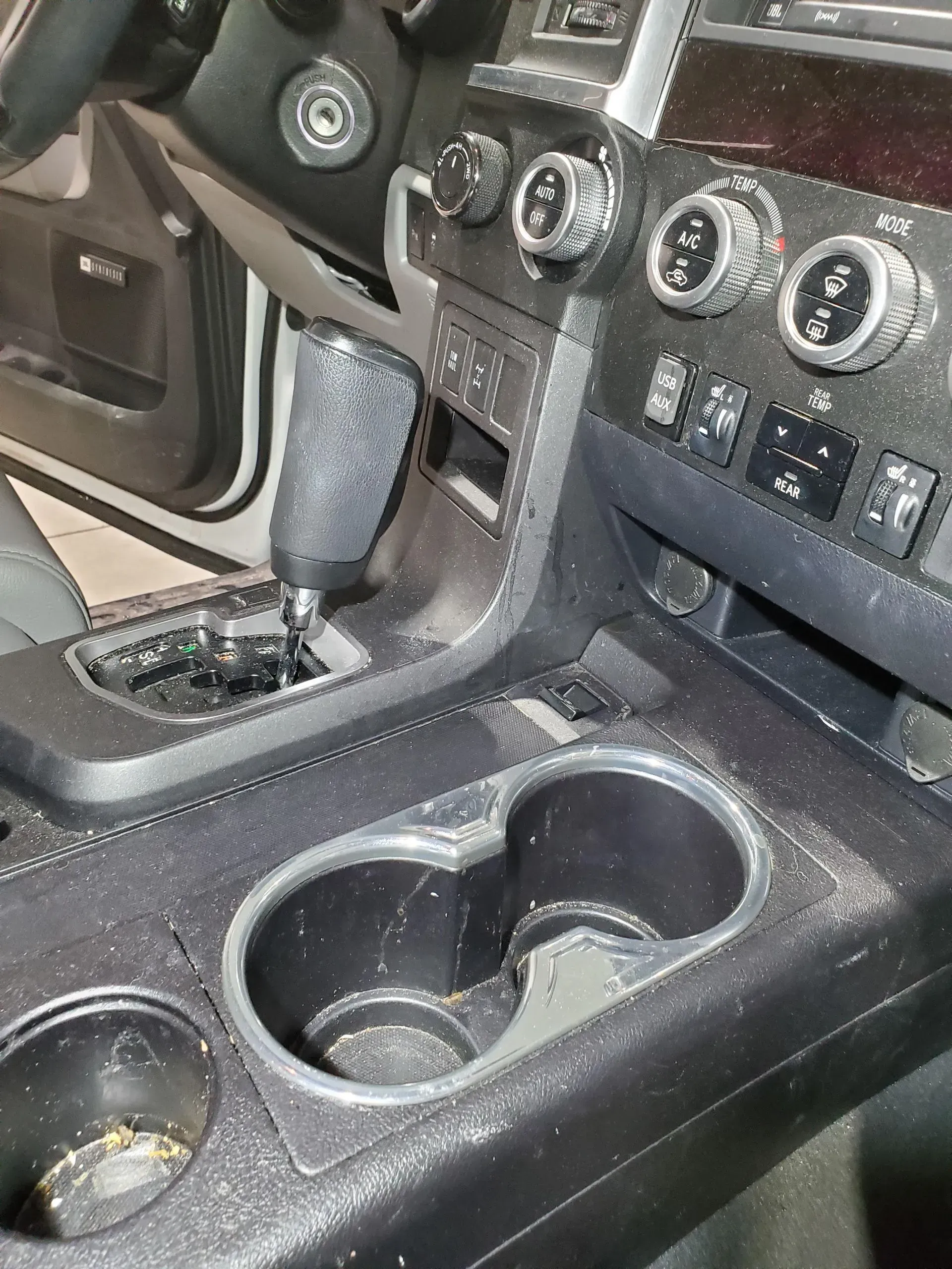 A close up of the dashboard of a car with cup holders.