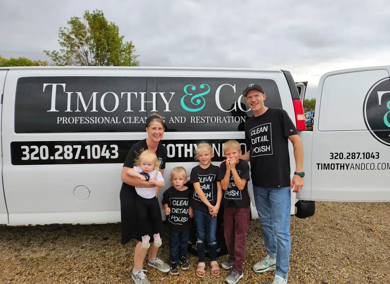 A family is posing for a picture in front of a timothy & co. van.