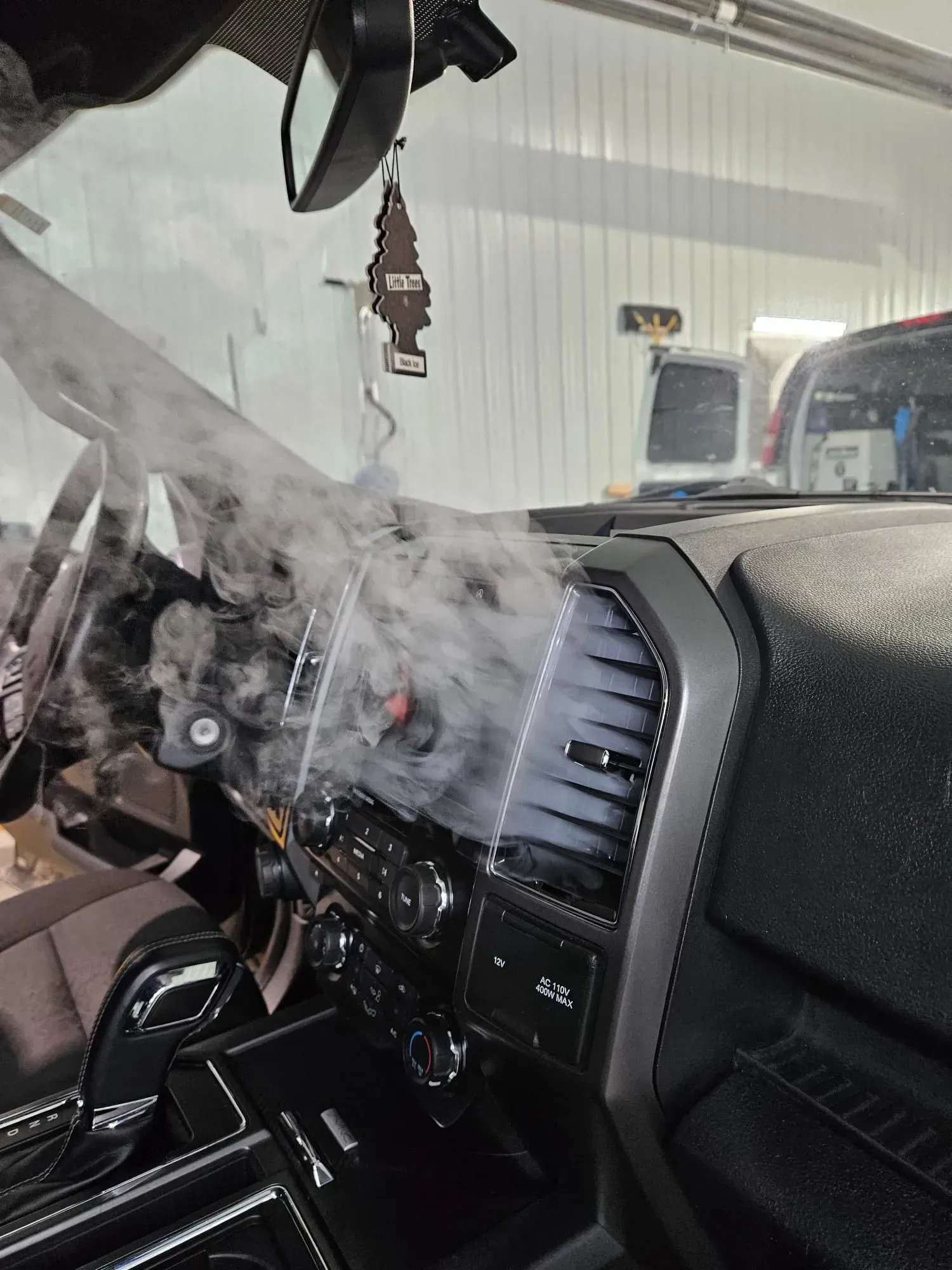 Smoke is coming out of the dashboard of a car.