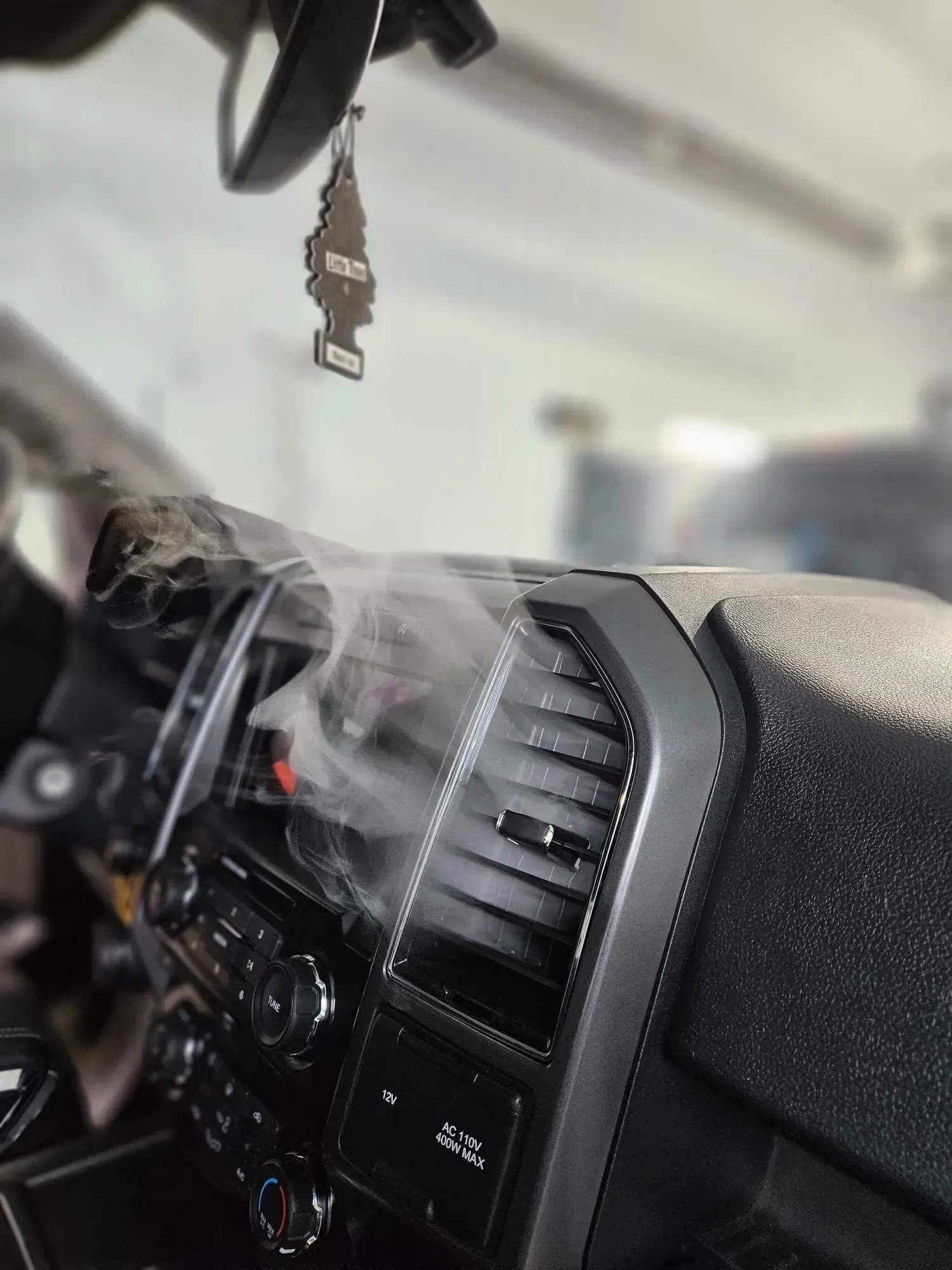 A close up of a car dashboard with smoke coming out of it.