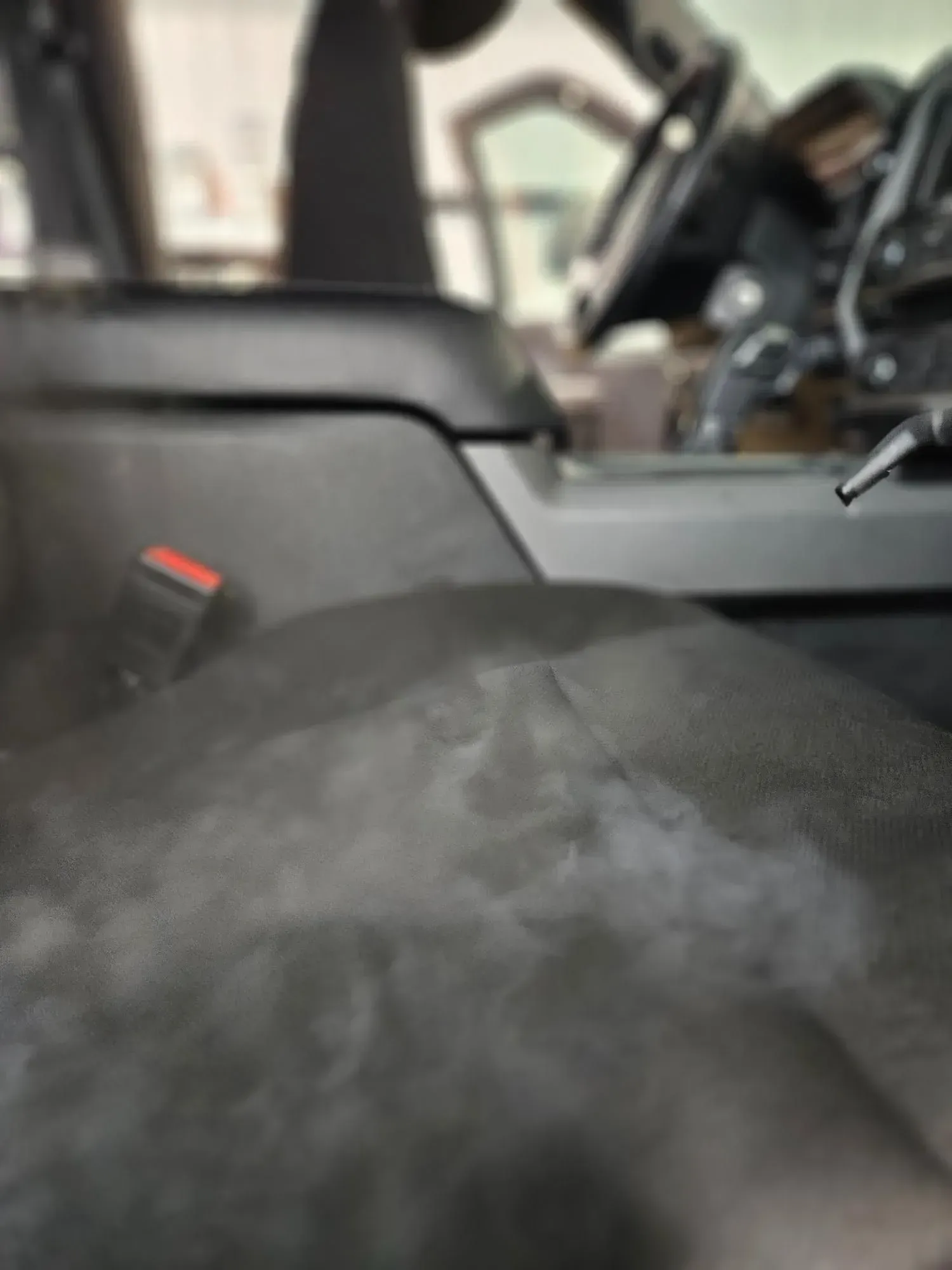 A close up of a car seat with a steering wheel in the background.