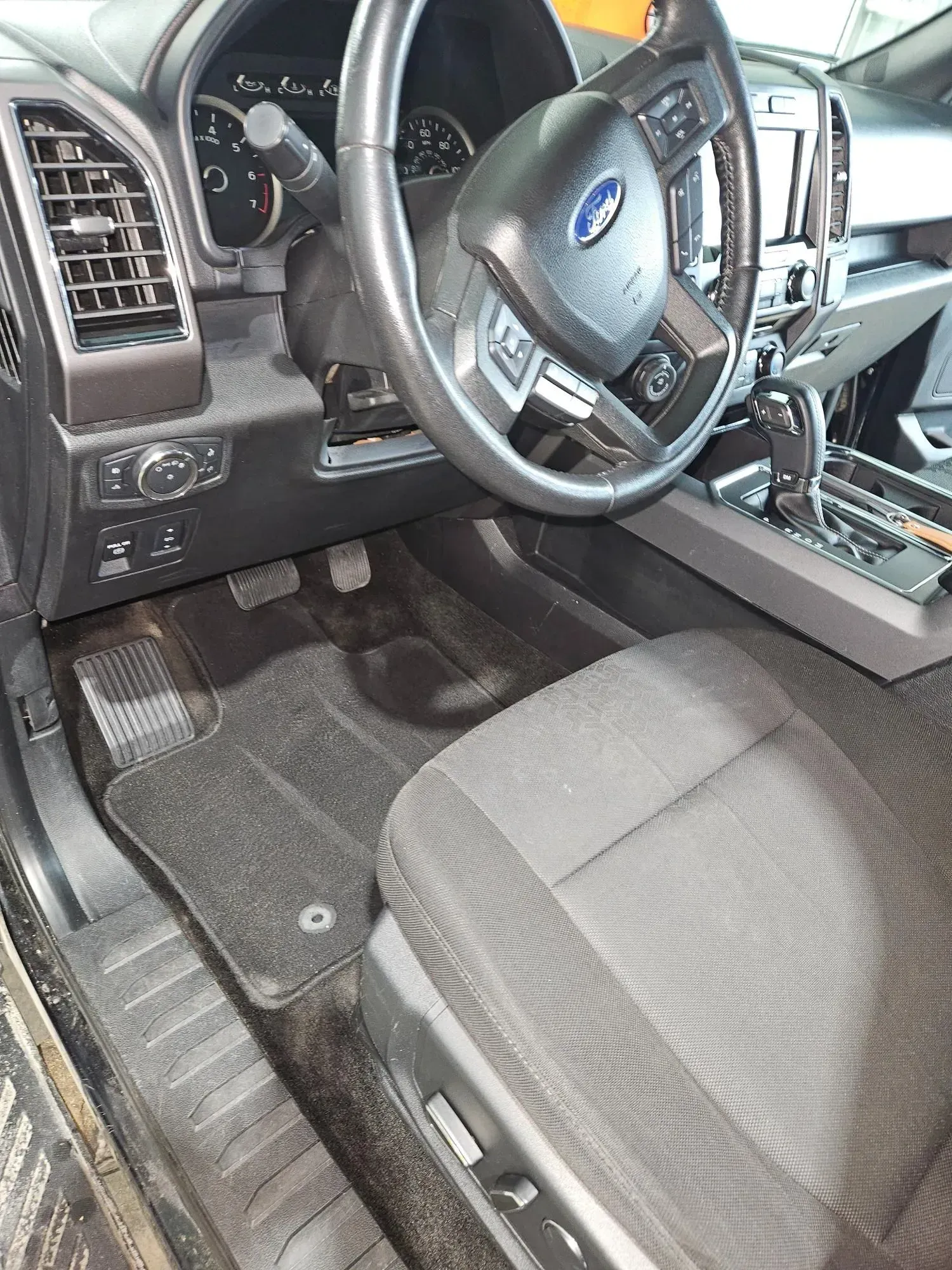 The interior of a ford f150 truck with a steering wheel and seats.