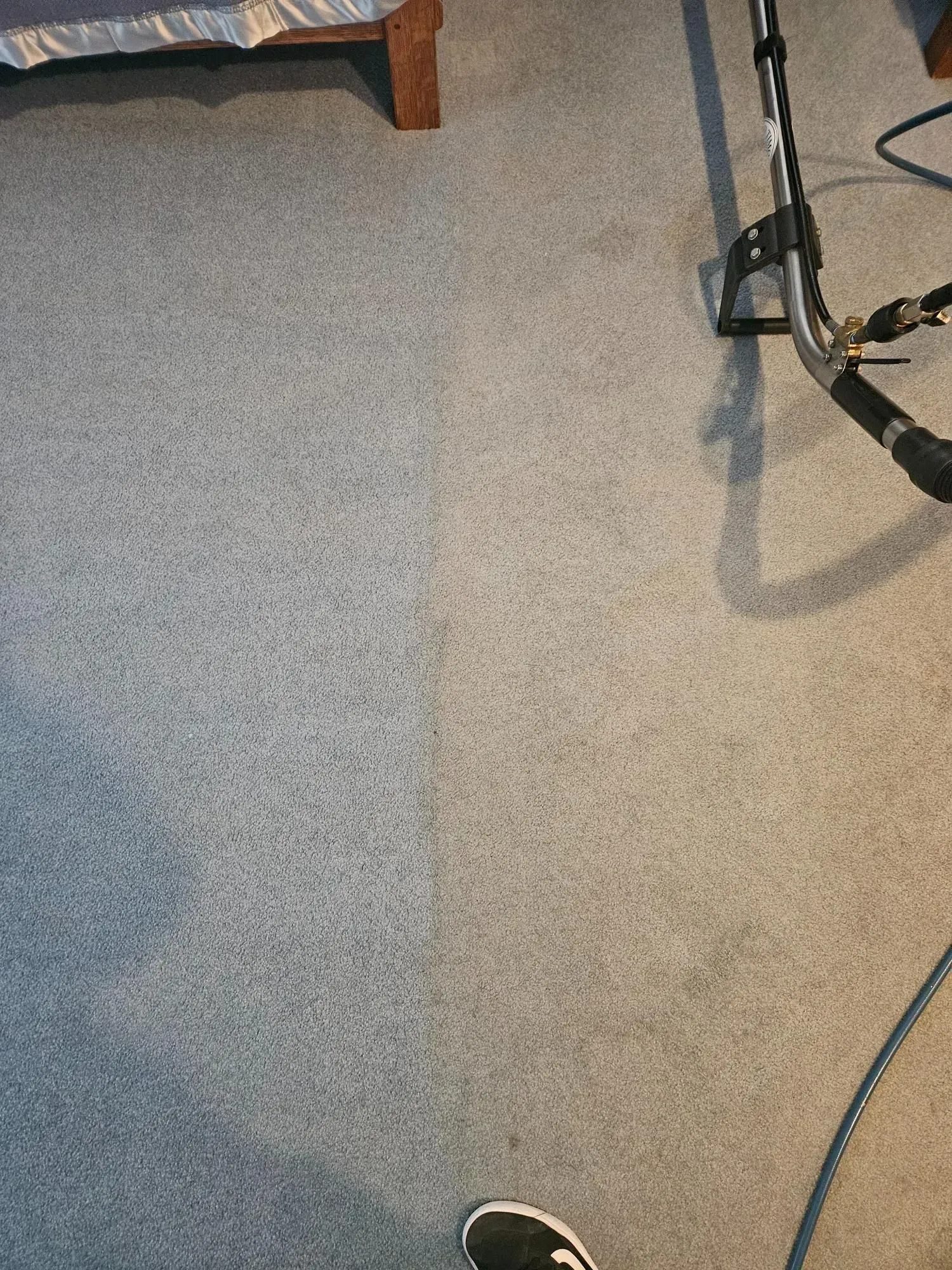 A person is standing on a carpet next to a vacuum cleaner.