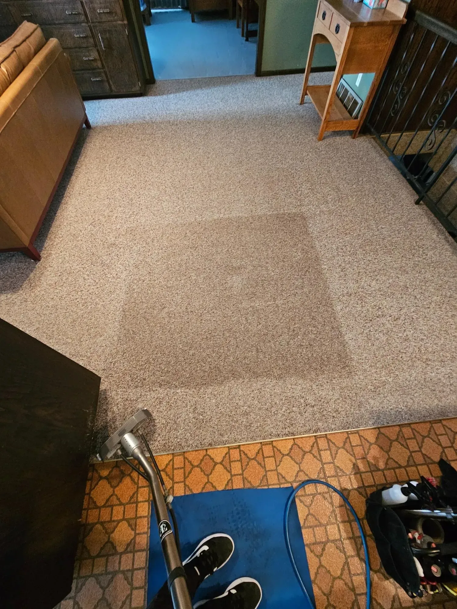 A person is cleaning a carpet in a living room with a vacuum cleaner.