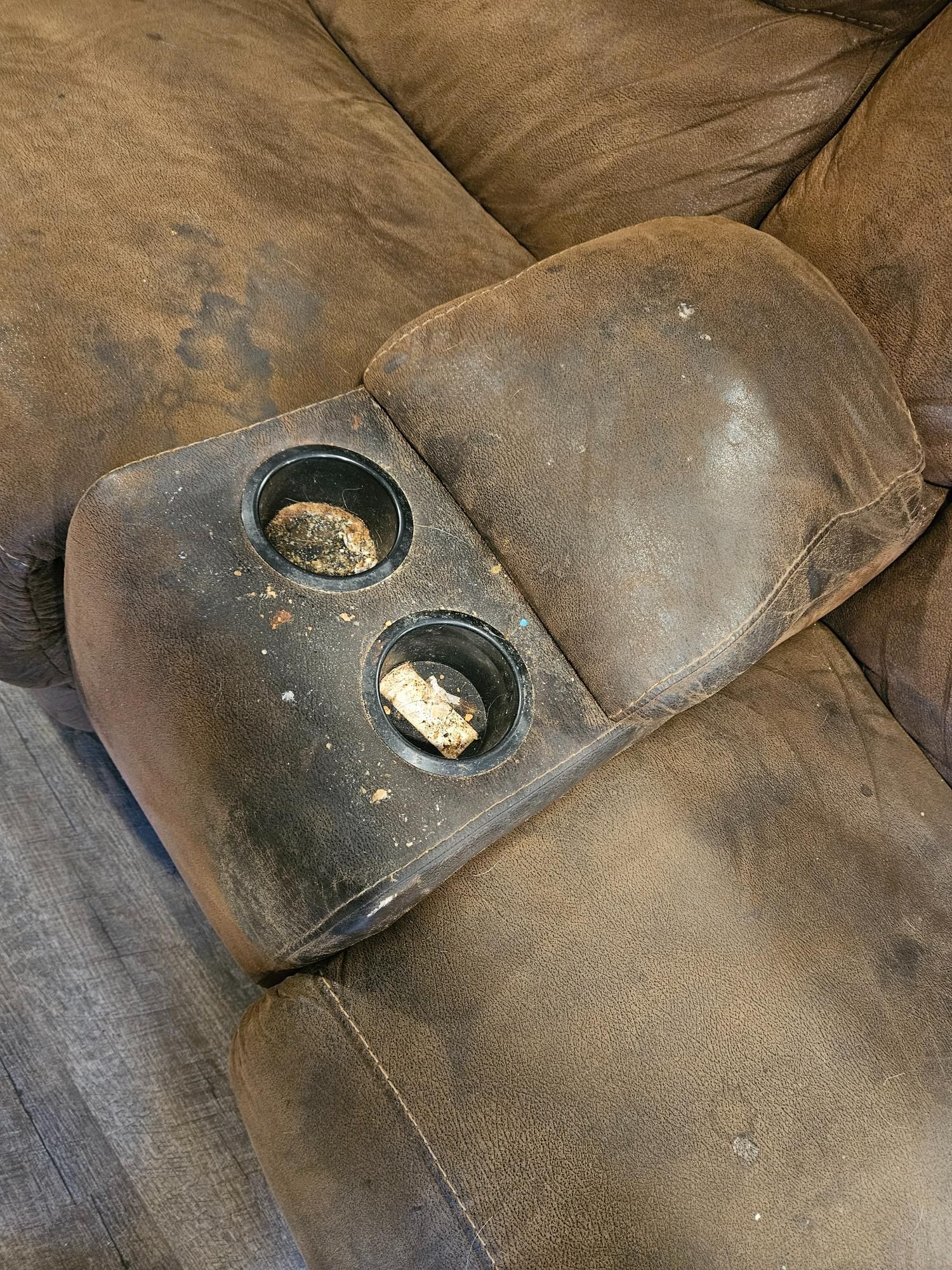A brown leather couch with two cup holders on the arm rests.
