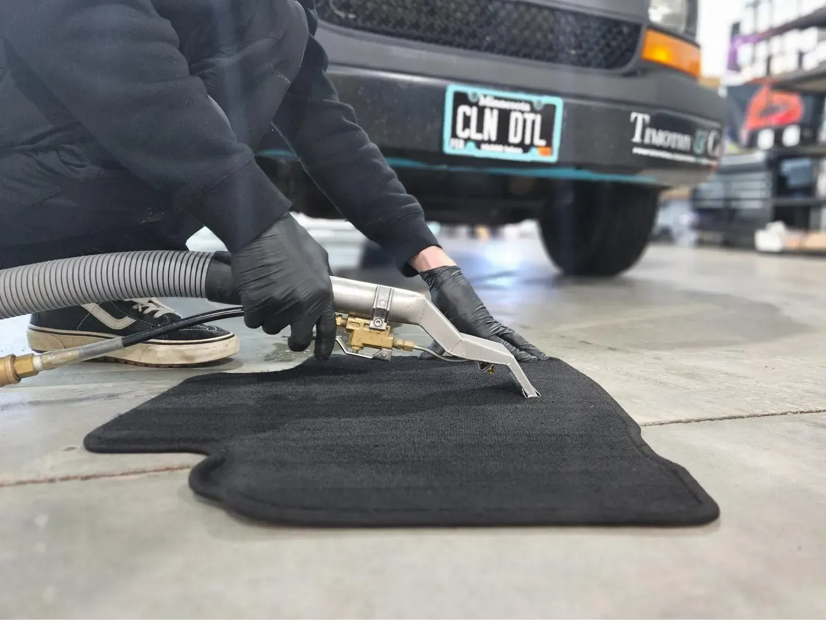 A person is cleaning a car mat with a vacuum cleaner.