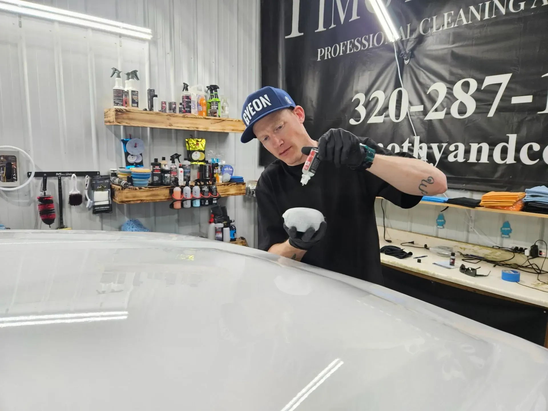A man is polishing a car in a garage.