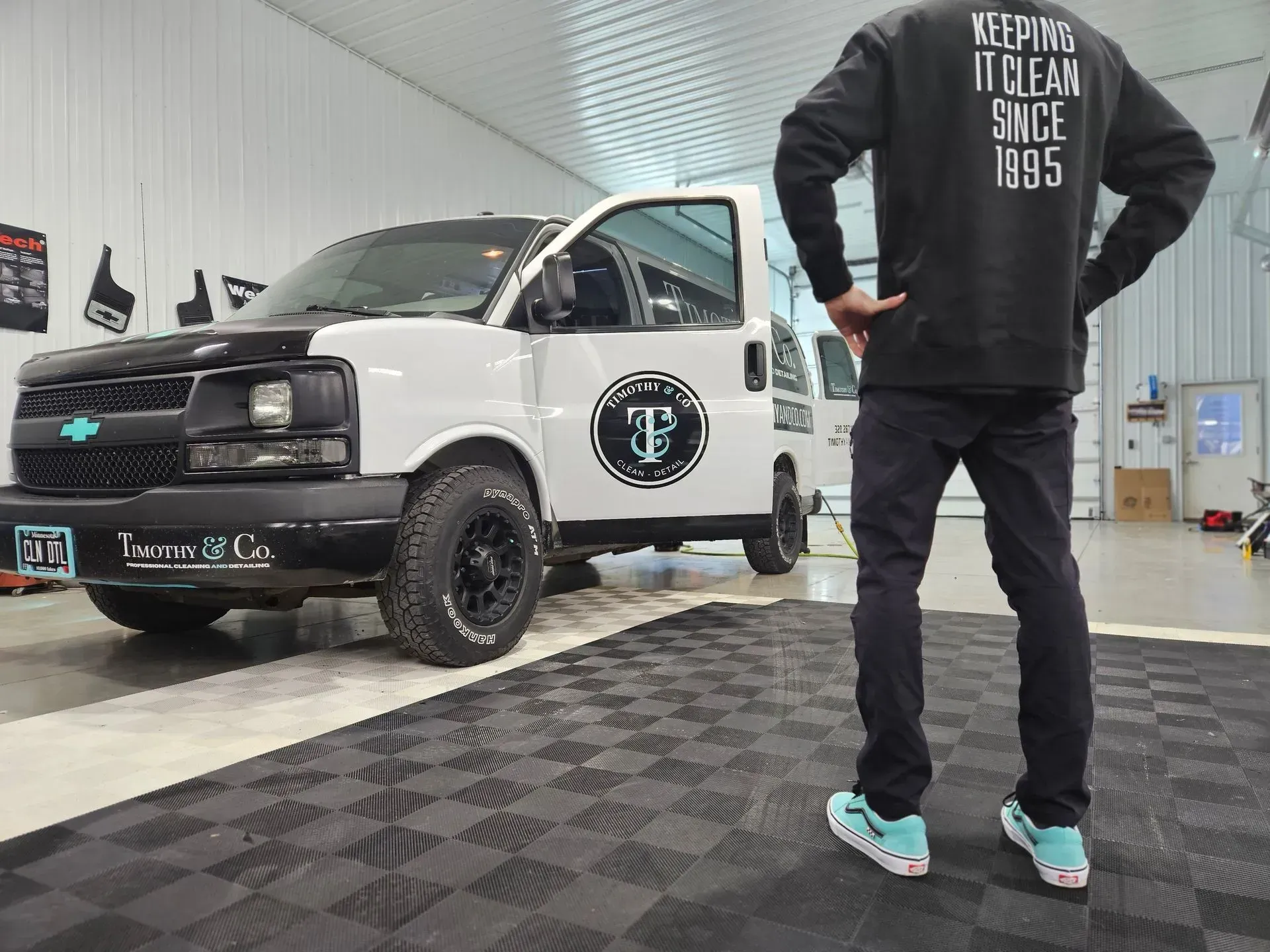A man in a black sweatshirt is standing in front of a white van.