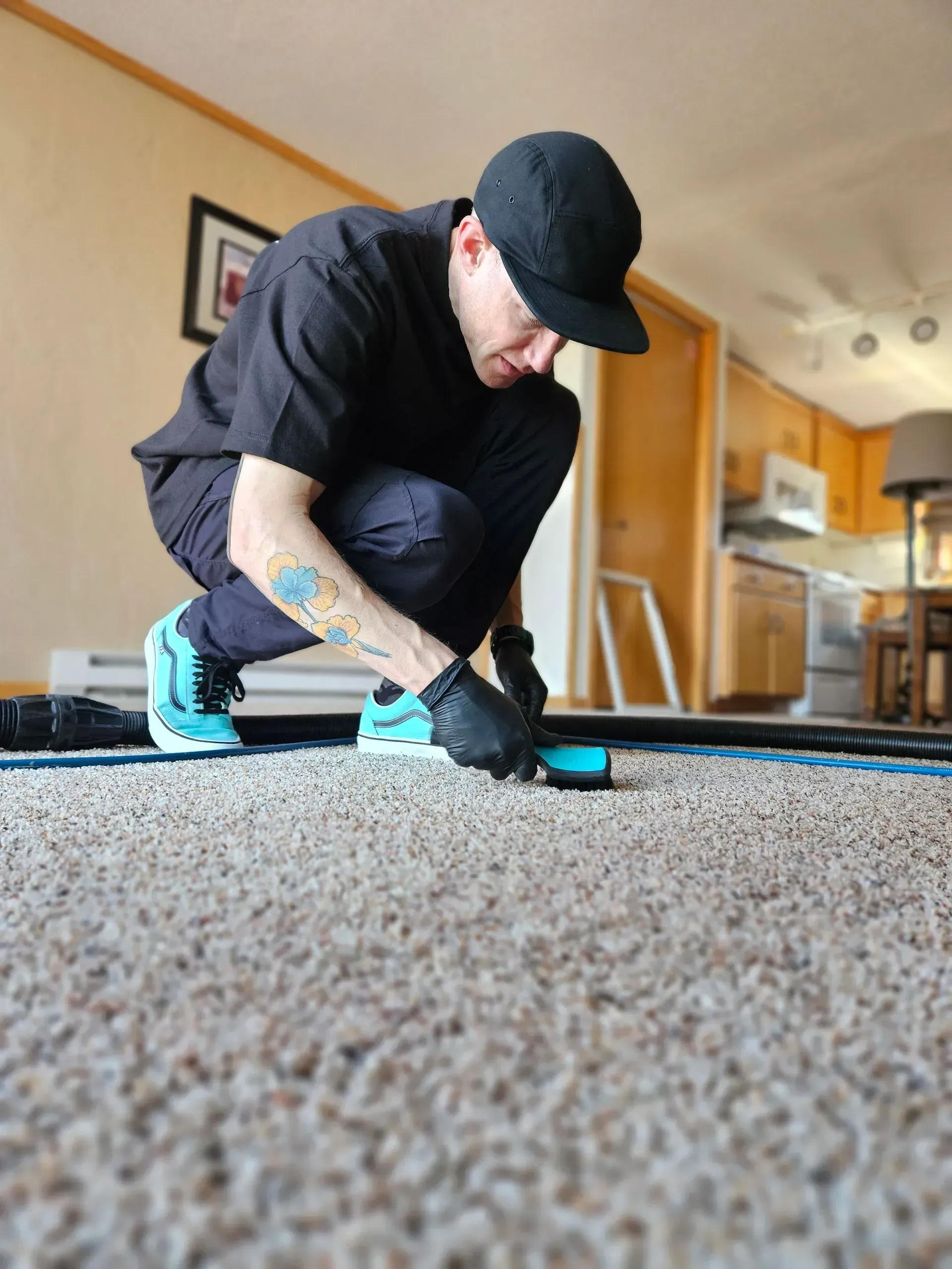 A man is kneeling down on a carpet in a living room.