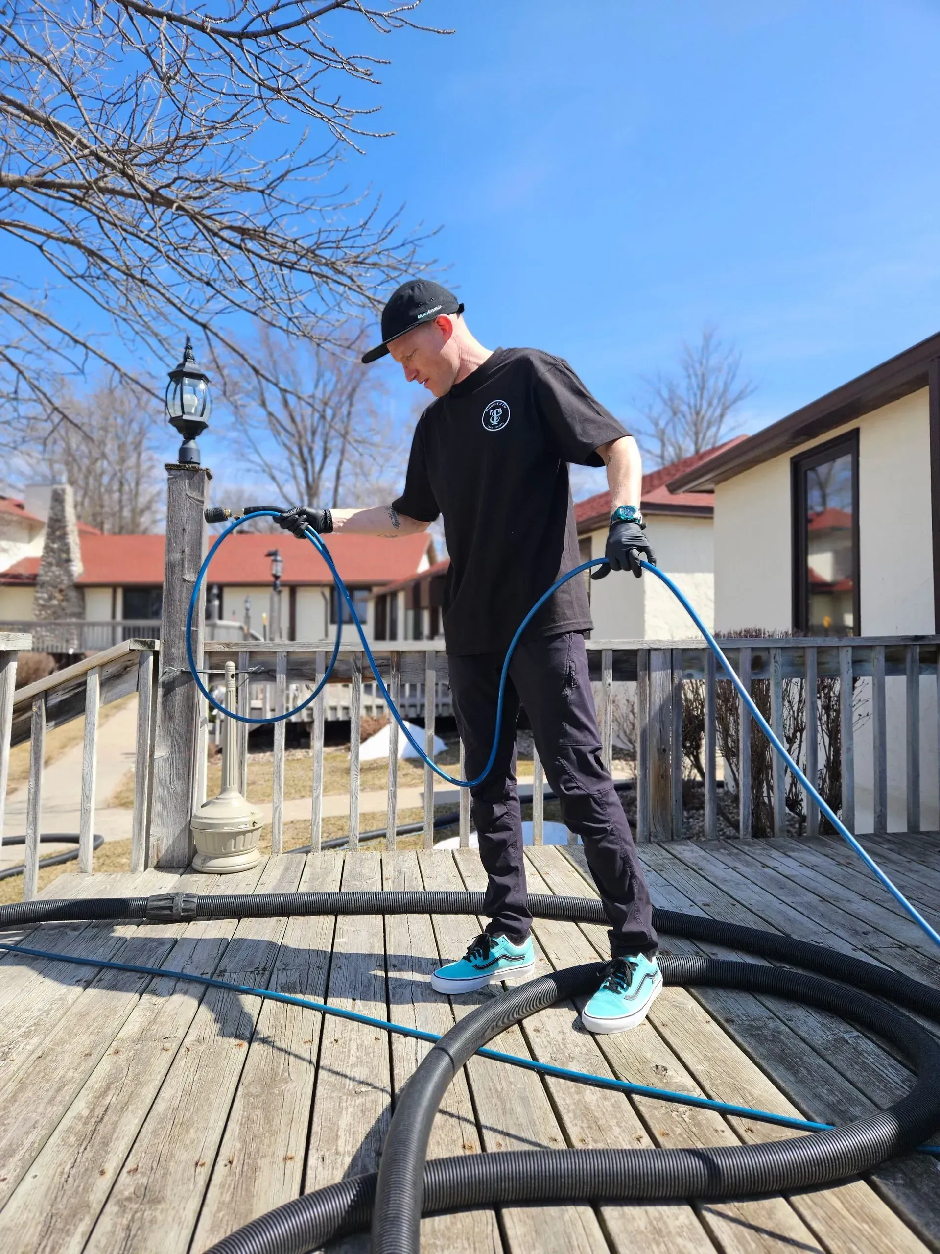 A man is standing on a deck holding a hose.