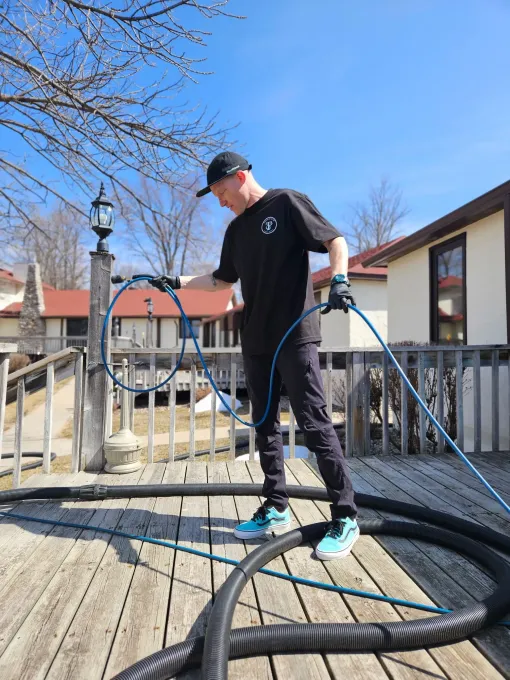 A man is standing on a deck holding a hose.