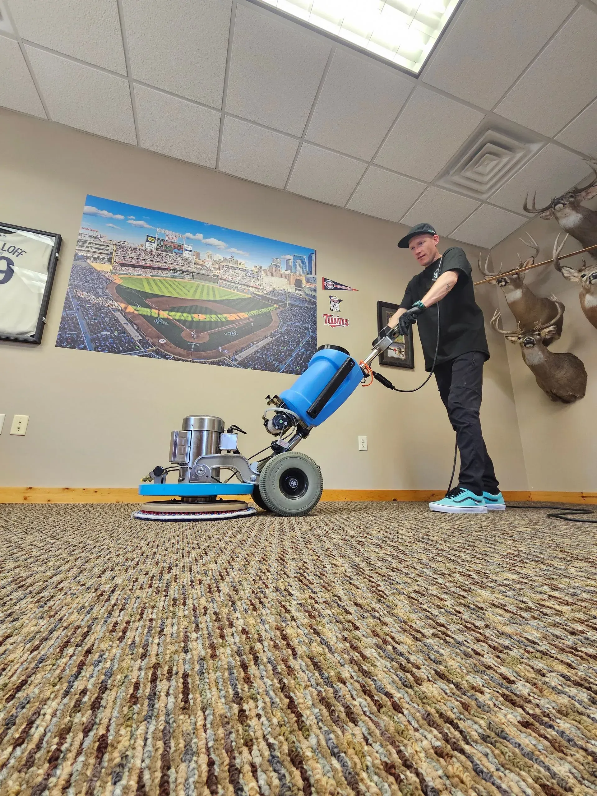 A man is cleaning a carpet with a machine in a room.