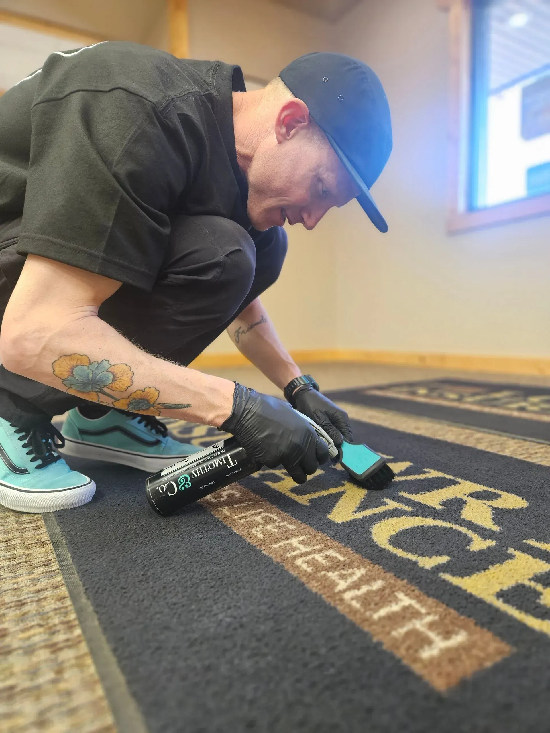 A man is cleaning a rug with a brush on it