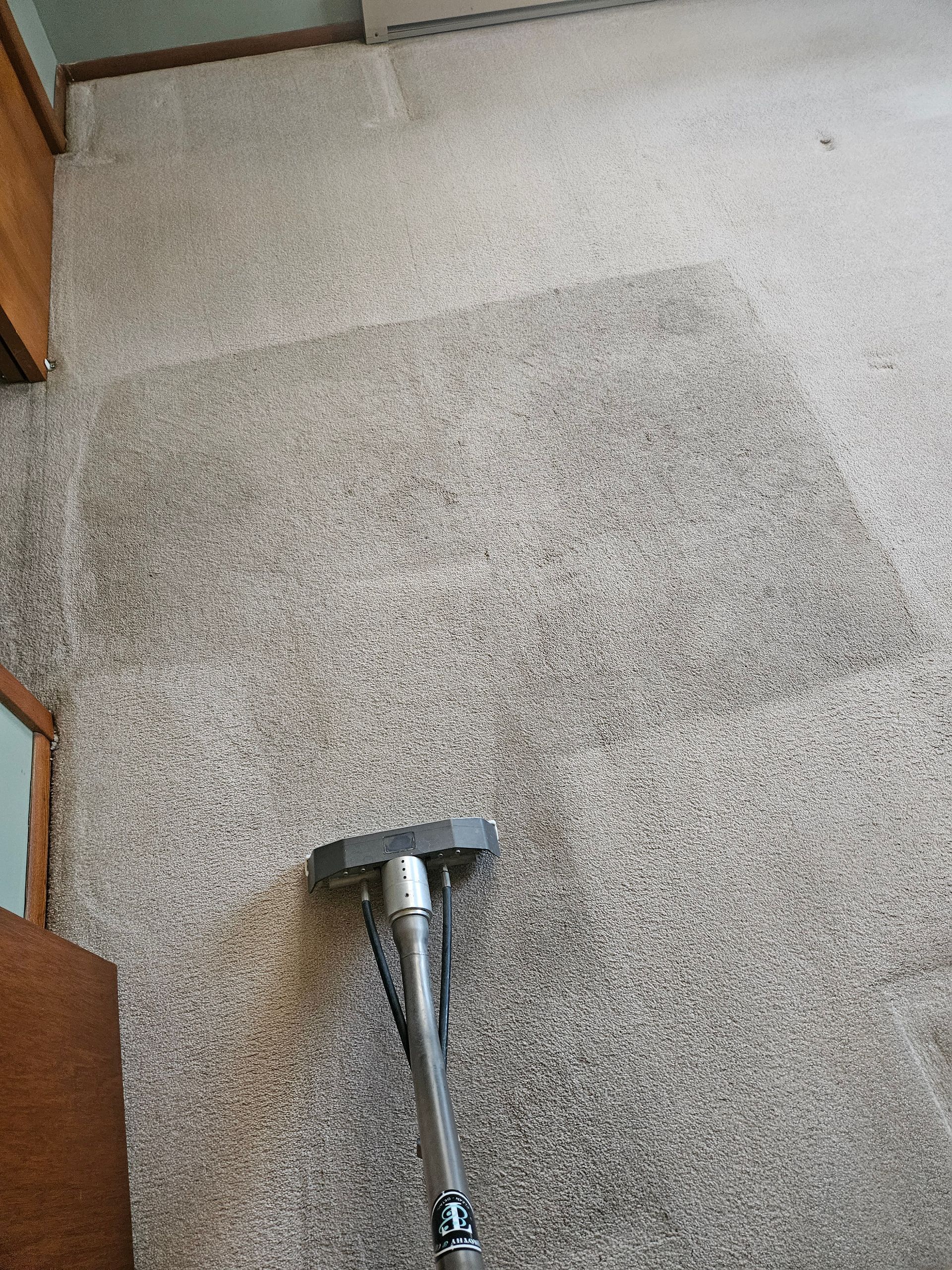 A vacuum cleaner is cleaning a carpet in a room.