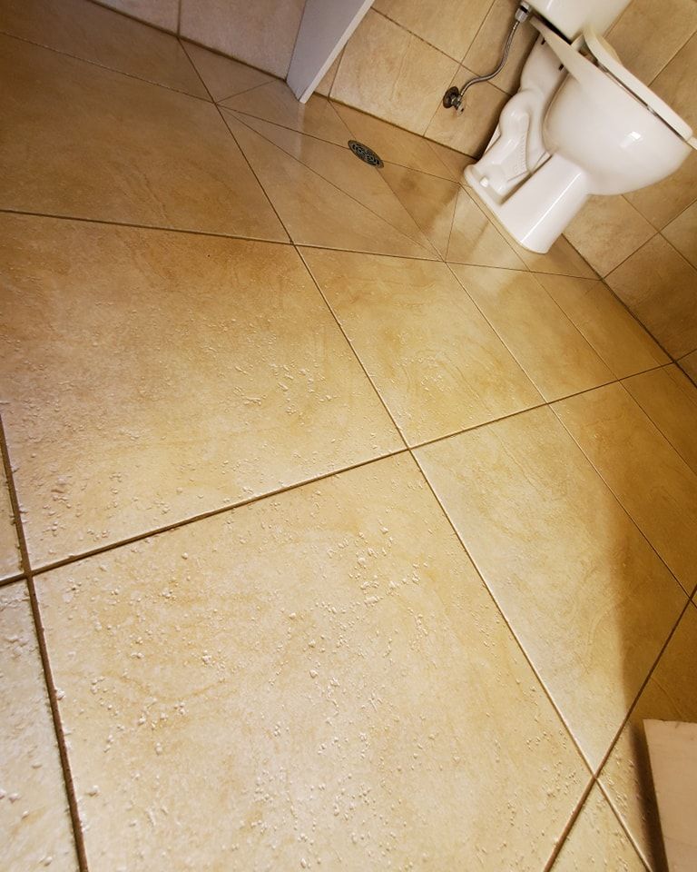 A toilet is sitting on a tiled floor in a bathroom.