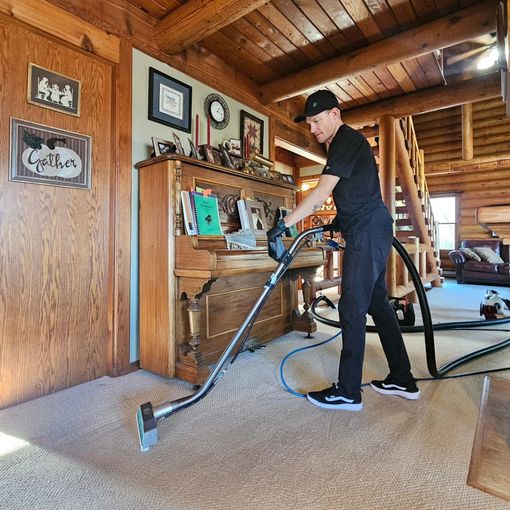 A man is using a vacuum cleaner to clean a carpet in a living room.