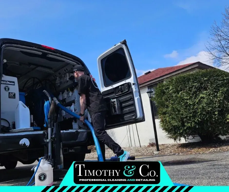A man is using a vacuum cleaner in the back of a van.