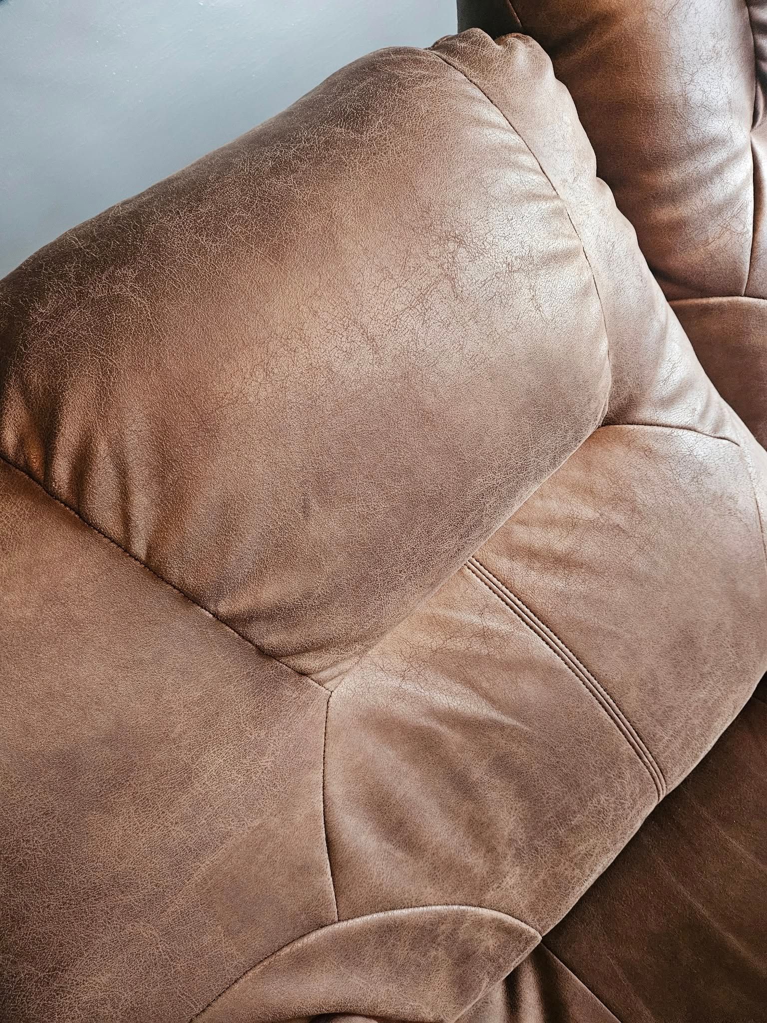 A close up of the back of a brown leather recliner.