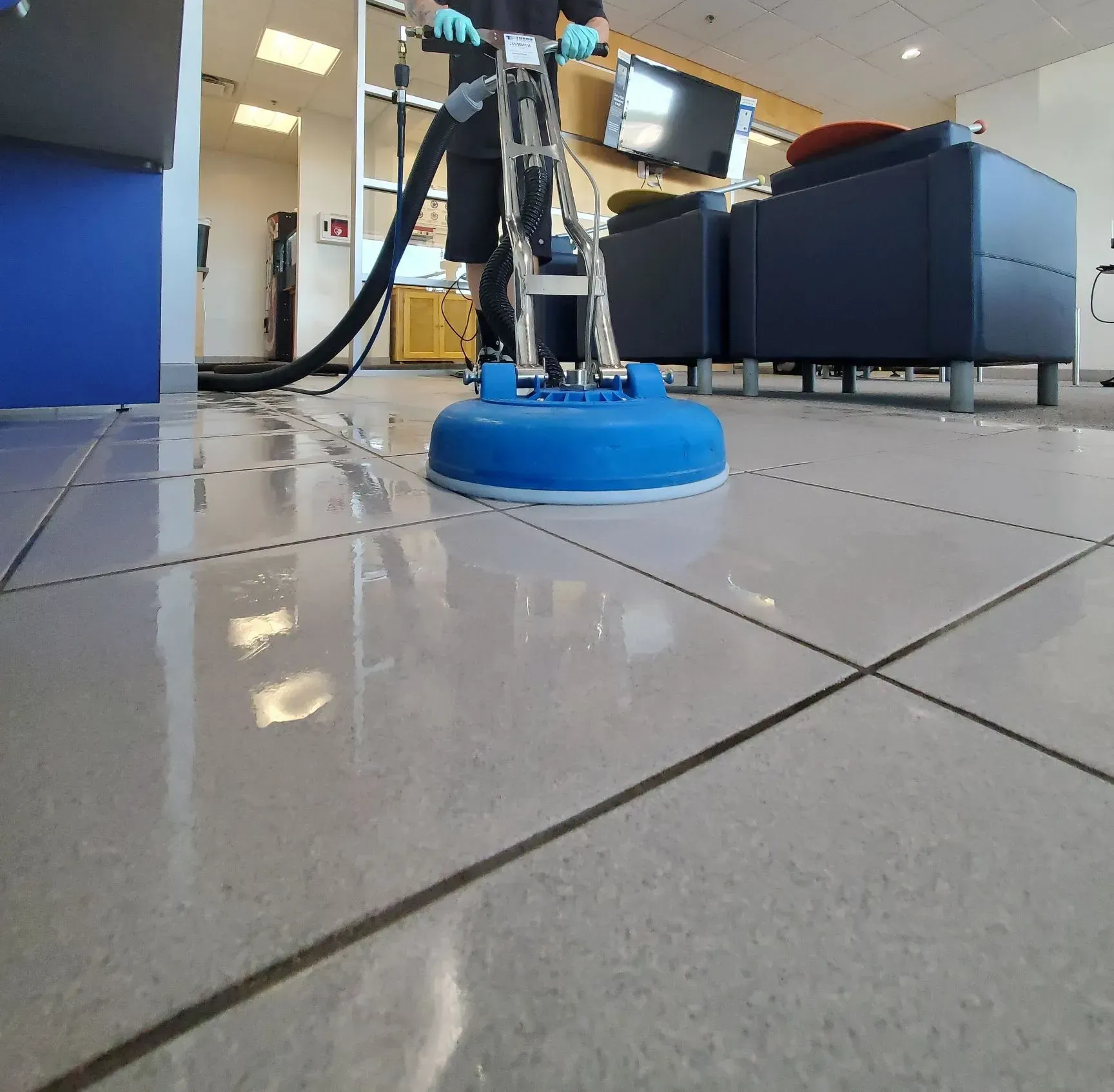 A person is cleaning a tiled floor with a machine