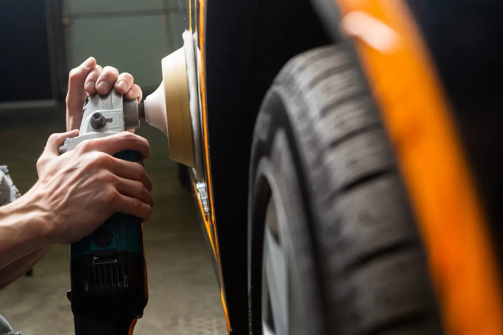 A person is polishing the side of a car with a machine.