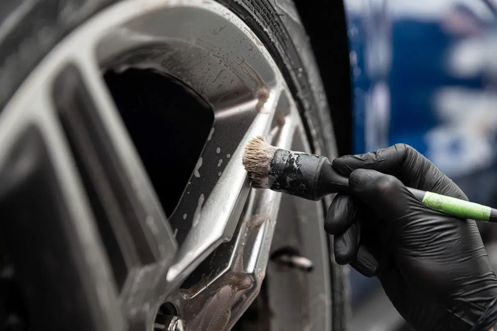 A person is cleaning a car wheel with a brush.