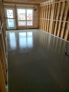 Une pièce avec un sol en béton et des murs en bois dans une maison en construction.