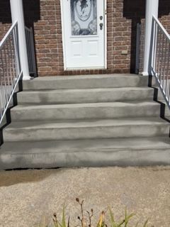 Une maison en briques avec des marches en béton menant à la porte d'entrée.