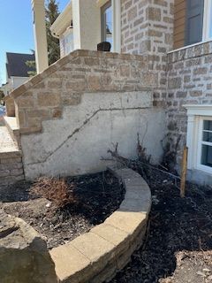 Un mur de pierre avec des escaliers menant à l'avant d'une maison.