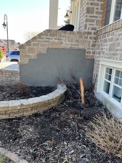 Un mur de briques avec une jardinière devant et une fenêtre.