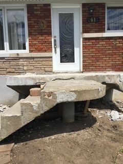 Un escalier en béton est en cours de construction devant une maison en briques.