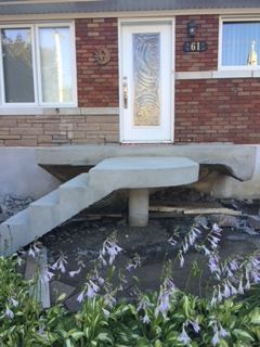 Une maison en briques avec un escalier en béton menant à la porte d'entrée.
