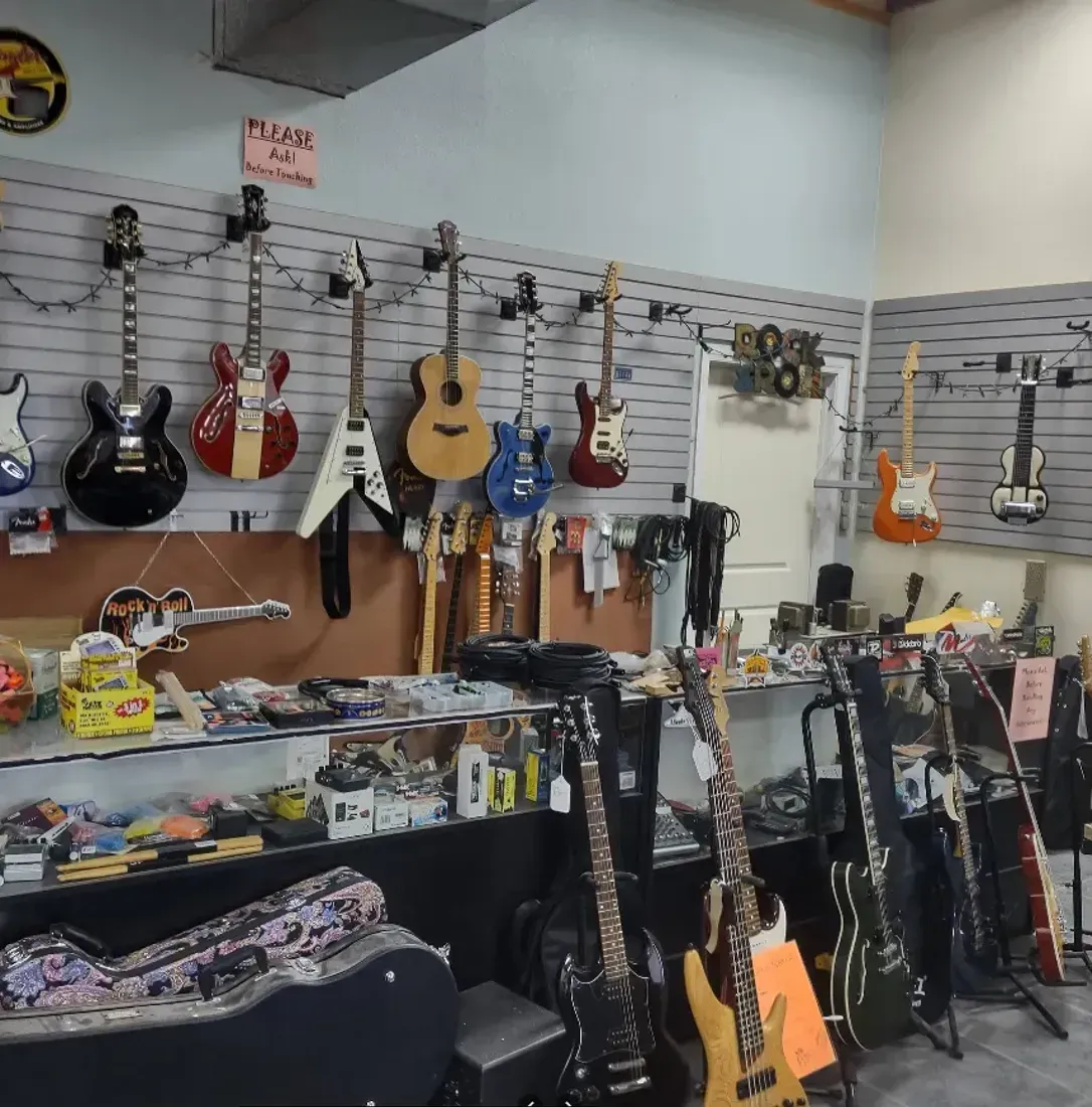 A room filled with lots of guitars hanging on the wall.